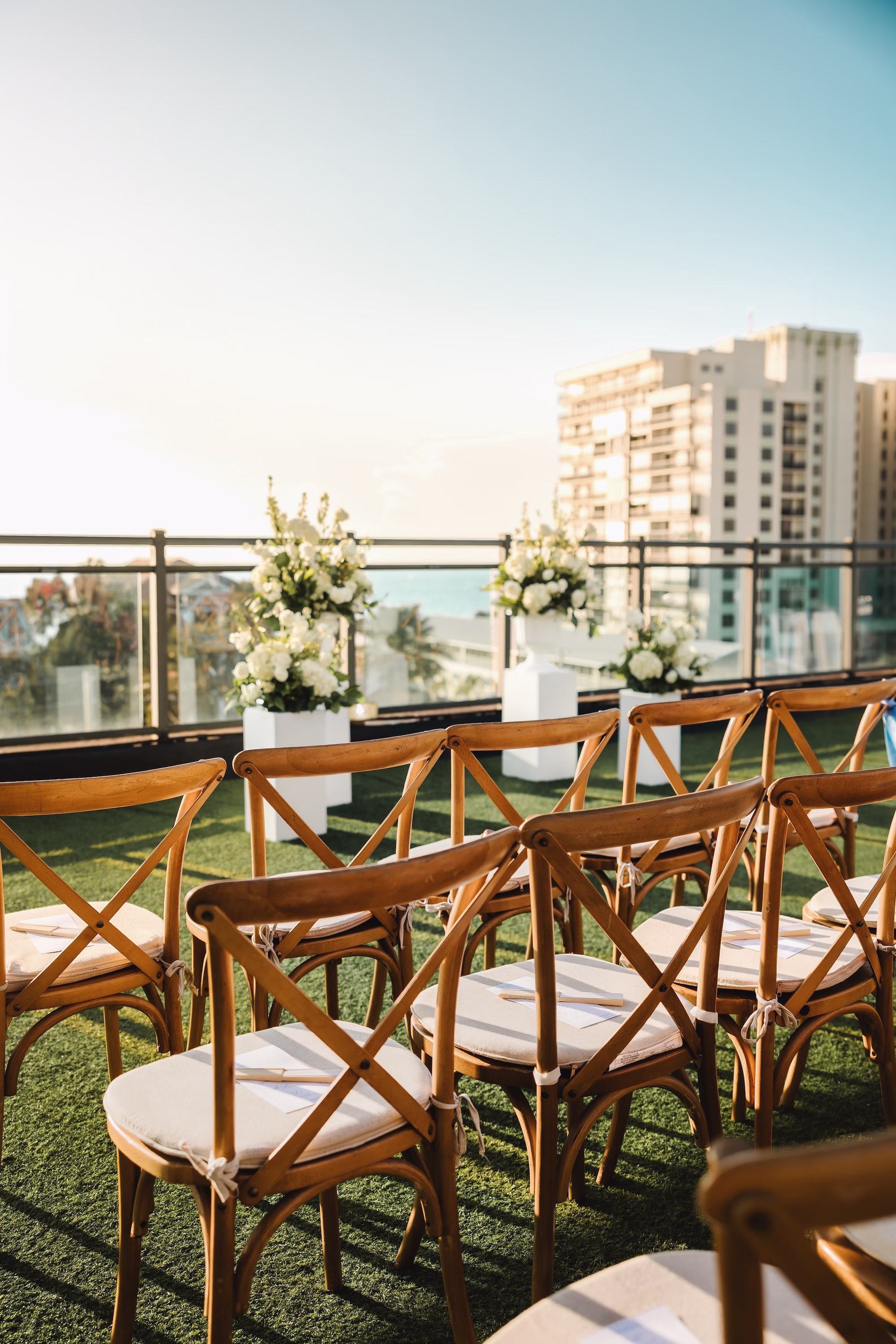 23Coastal Blue and White Rooftop Florida Wedding Ideas St Pete Venue Hotel Zamora - Romantic Blue Coastal St. Pete Beach Wedding | The Hotel Zamora Coastal Beachfront Rooftop Wedding Ceremony Ideas | Monochromatic White Floral Arrangement Altar Decor Ideas | Rustic Wooden Cross Back Ceremony Chairs Ideas | St Pete Beach Wedding Venue Hotel Zamora | St Petersburg Wedding Planner Seashine Weddings