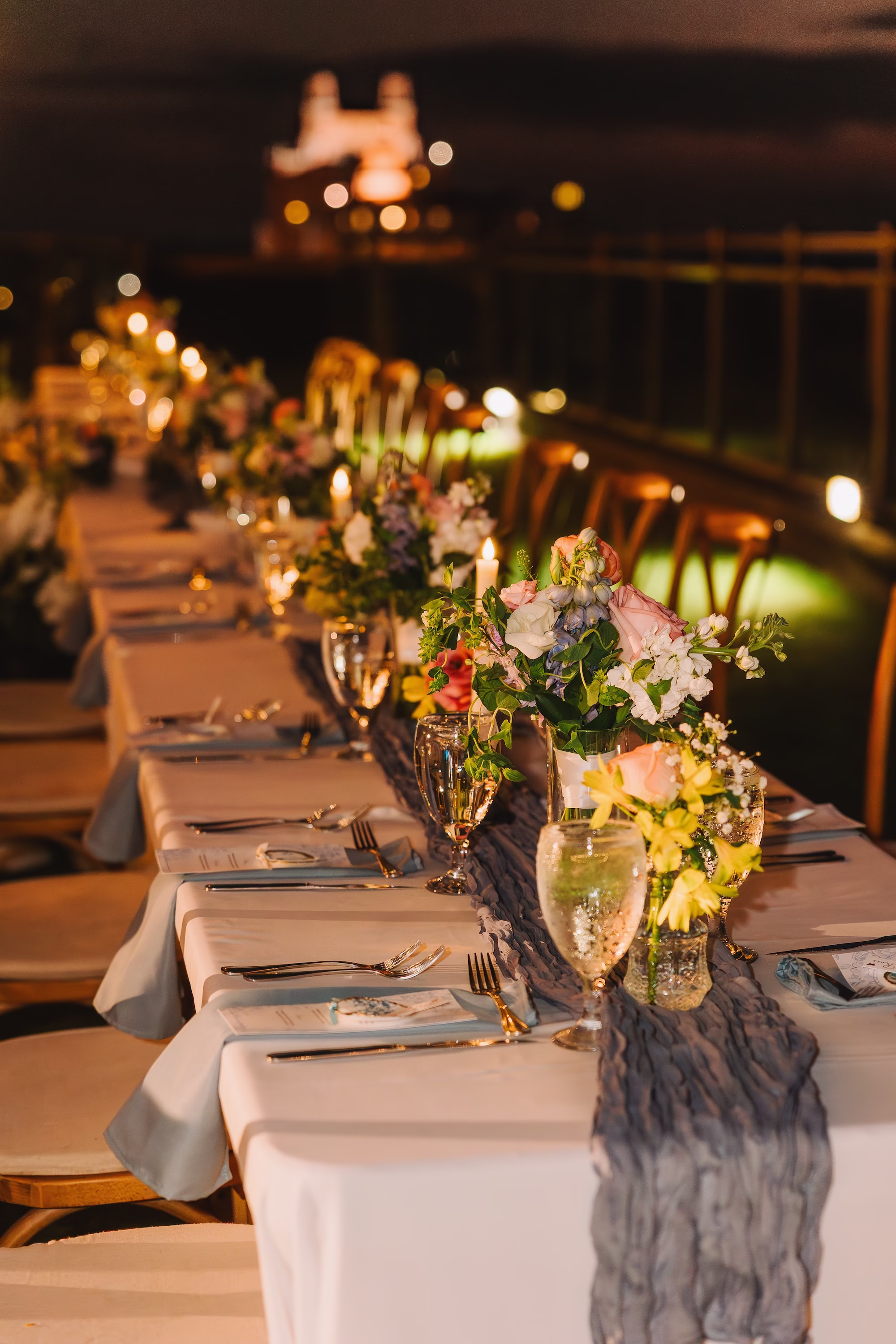 44Coastal Blue and White Rooftop Florida Wedding Ideas - Romantic Blue Coastal St. Pete Beach Wedding | The Hotel Zamora Coastal Elegant Waterfront Rooftop Wedding Reception Inspiration | Long Feasting Table with Rustic Wooden Cross Back Chairs and White Linens and Dusty Blue Crepe Table Runner Tablescape Ideas | Small Colorful Floral Centerpieces Inspiration | St Petersburg Wedding Planner Seashine Weddings