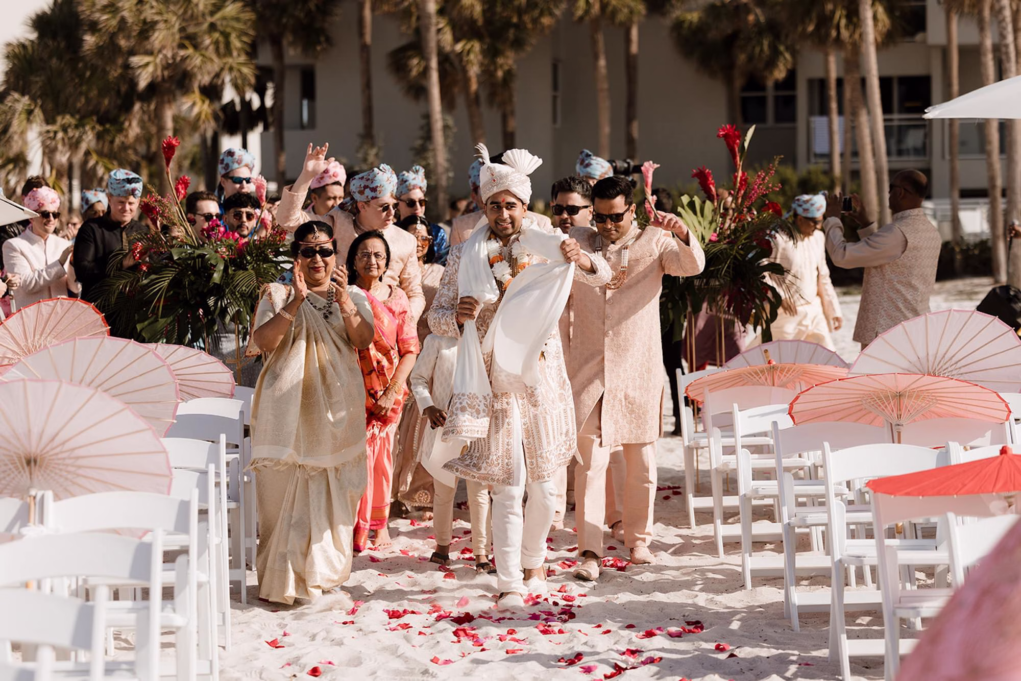 23Tropical Pink and Red Sarasota Beach Indian Wedding Ceremony - Vibrant Pink and Gold Multicultural Sarasota Wedding | Powel Crosley Estate Groom Walks Down Wedding Ceremony Aisle Wedding Portrait | Traditional Indian Wedding Ceremony Inspiration | Groom Beaded Off-White Sherwani Inspiration | Indian Culture Wedding Ideas | White Ceremony Chairs with Rose Petal Aisle Decor Inspiration | Red and Pink Delicate Umbrellas Parasails Favor Ideas | Sarasota Beach Event Venue The Resort at Longboat Key Club | Photographer Evoke Photo and Film