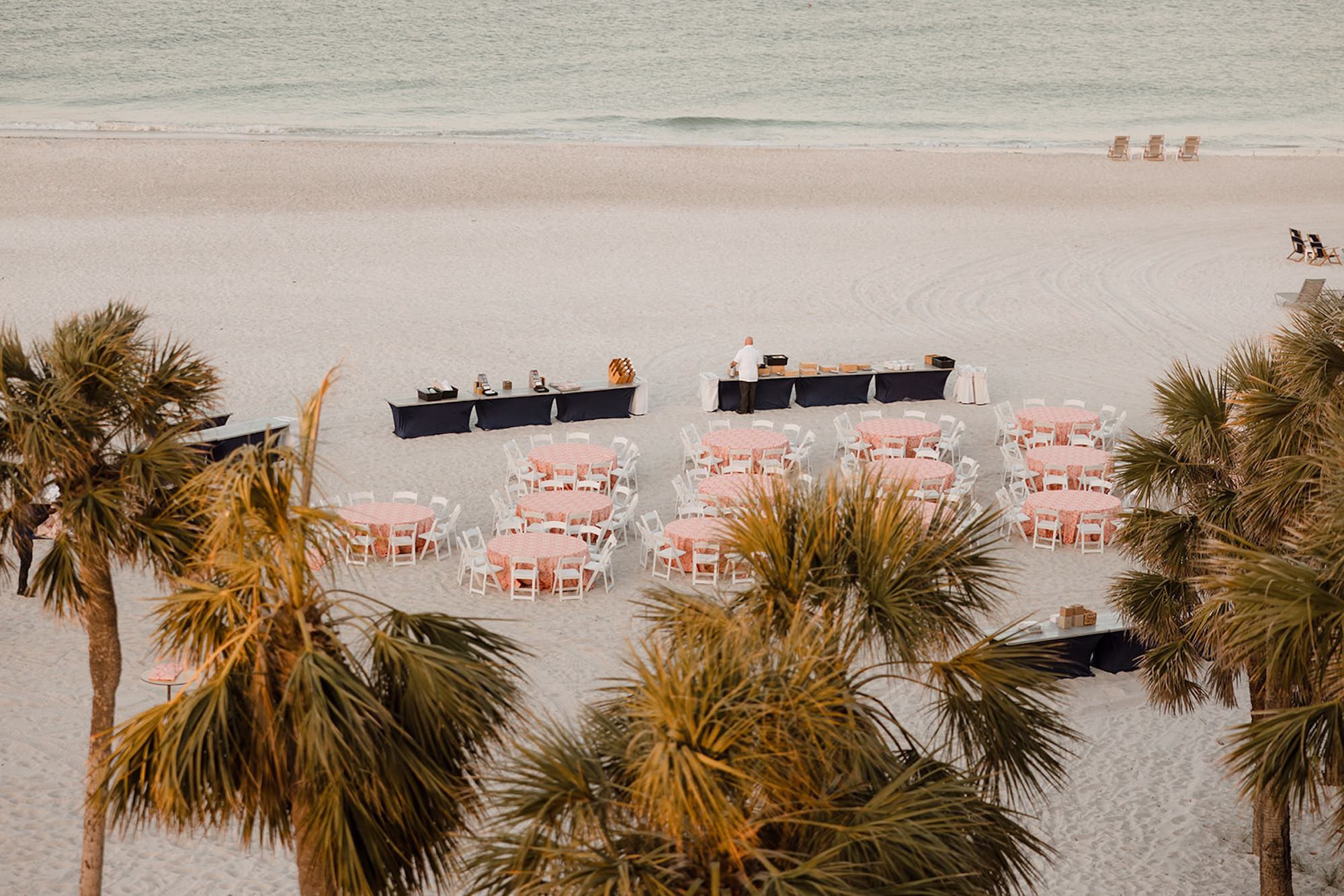 28Tropical Pink and Red Sarasota Beach Indian Wedding Ceremony - Vibrant Pink and Gold Multicultural Sarasota Wedding | Powel Crosley Estate Oceanfront Wedding Ceremony Reception Ideas | Large White Beach Umbrellas at Round Dining Tables with Coral Decorative Patterned Linens and White Folding Chairs Wedding Ceremony Decor Inspiration | Potted Green Plant in a Minimalist White Vase Centerpiece Decor Ideas | Sarasota Beach Event Venue The Resort at Longboat Key Club