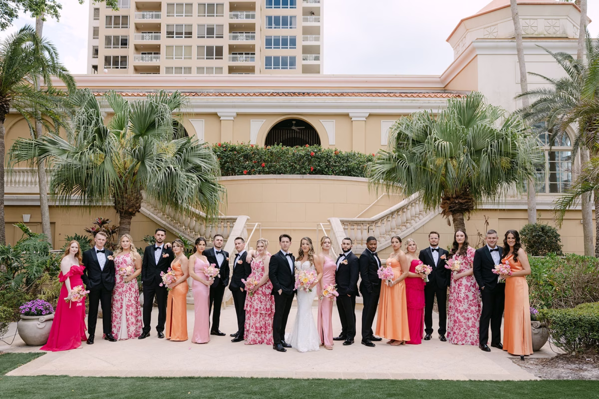 29Luxurious Whimsical Colorful Tented Florida Wedding - Luxurious, Pastel Garden Tented Wedding | Ritz Carlton Sarasota Bride and Groom with Wedding Party Wedding Portrait | Pink, Floral, and Orange Bridesmaid Dress Inspiration | Whimsical Garden Outdoor Wedding Ideas