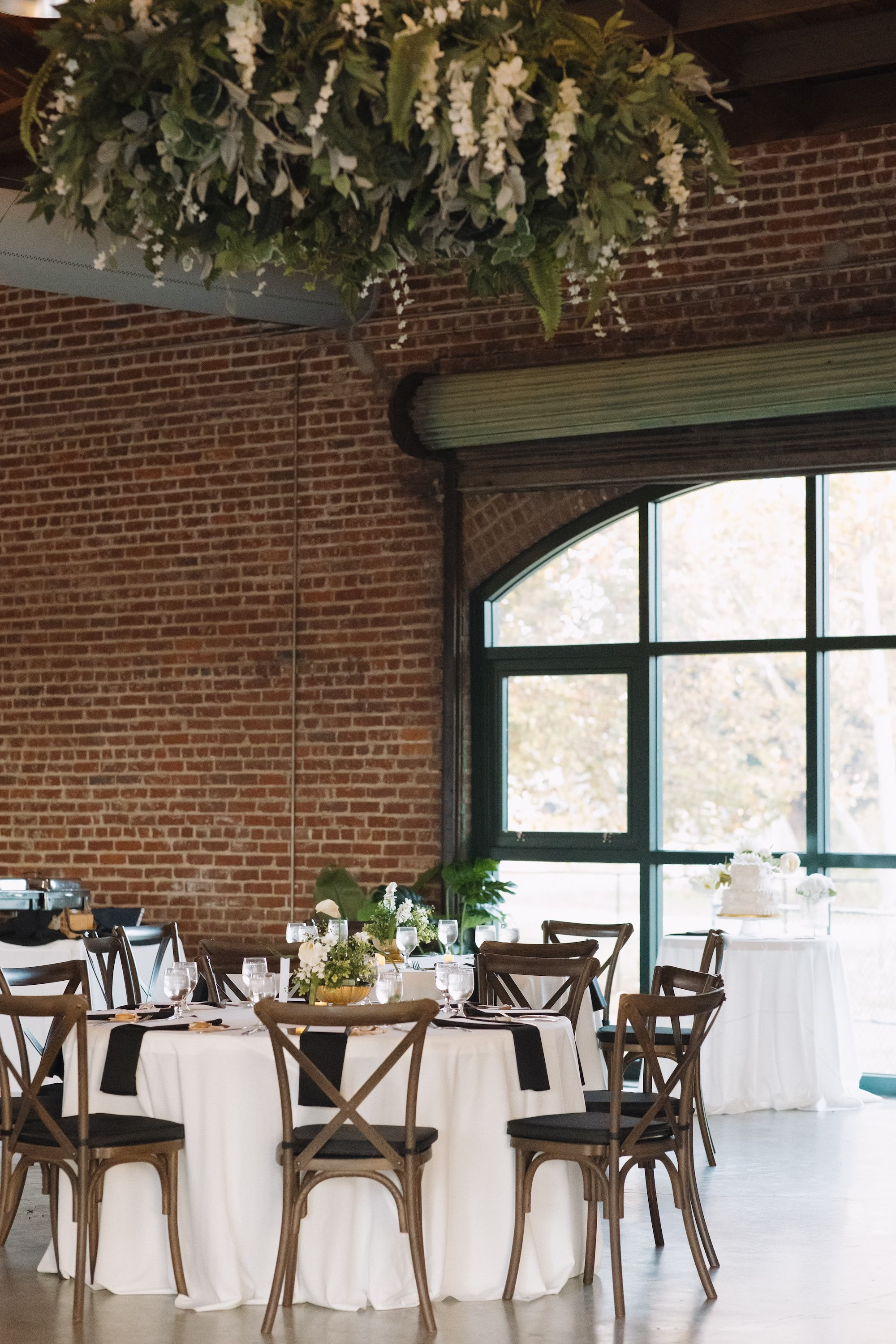 31Classic White and Green Florida Wedding Inspiration St Pete Venue Events at Morean Historic Train Station - Classic, White and Green St. Pete Wedding | Events at Morean Historic Train Station Modern Industrial Rustic Exposed Brick Ballroom Wedding Reception | Rustic Wooden Chairs at Round Tables with White Table Linens and Olive Green Napkins Inspiration | Short Simple Romantic Moss Centerpieces with White Floral Ideas | Classic Timeless Natural Wedding Theme Inspiration | Greenery Fern and Eucalyptus with White Floral Hanging Flower Ceiling Installation Reception Decor Inspiration | Venue St. Petersburg Venue Morean Center for Clay