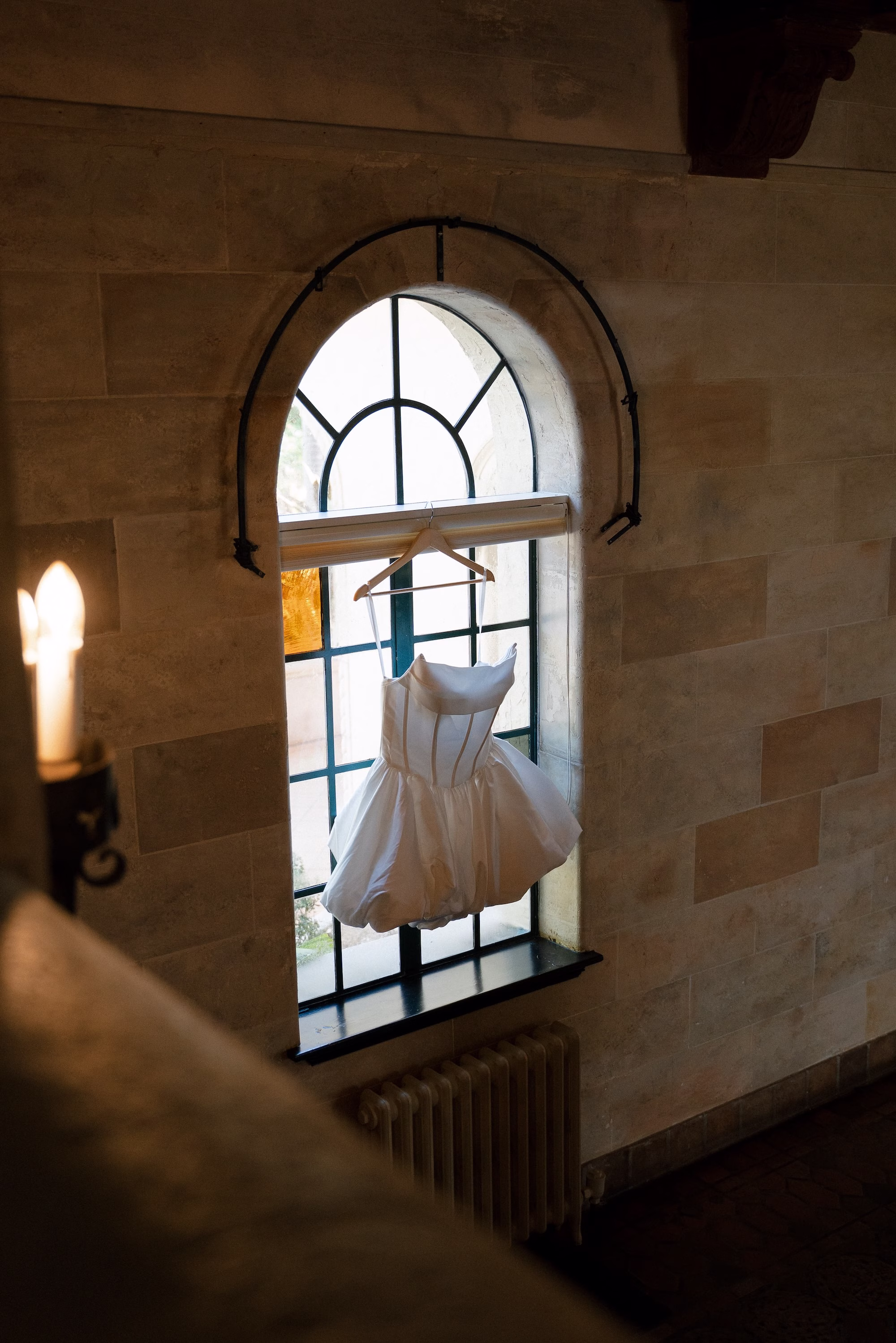 Short Strapless Wedding Gown Hanging in Window Wedding Portrait