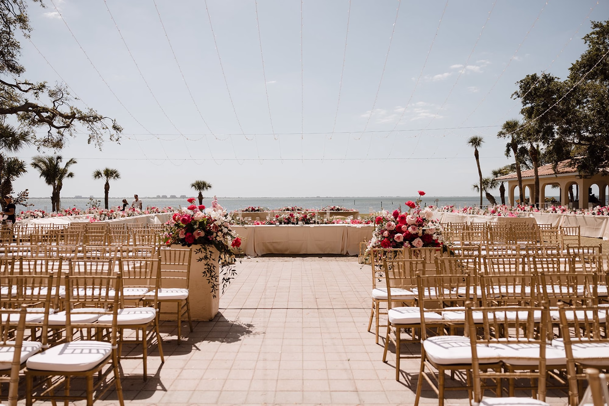 51Romantic Pink and Gold Waterfront Florida Wedding Sarasota Venue Powel Crosley Estate - Vibrant Pink and Gold Multicultural Sarasota Wedding | Powel Crosley Estate Garden Romantic Outdoor Wedding Reception | Lush Full-Length Floral Centerpieces Arrangements with Pink, Red and Blush Roses, Hydrangeas and Greenery Reception Decor Inspiration | String Lights and Gold Chairs Reception Ceremony Decor Ideas | Tampa Bay Wedding Photographer Evoke Photo and Film | Sarasota Wedding Venue Powel Crosley Estate