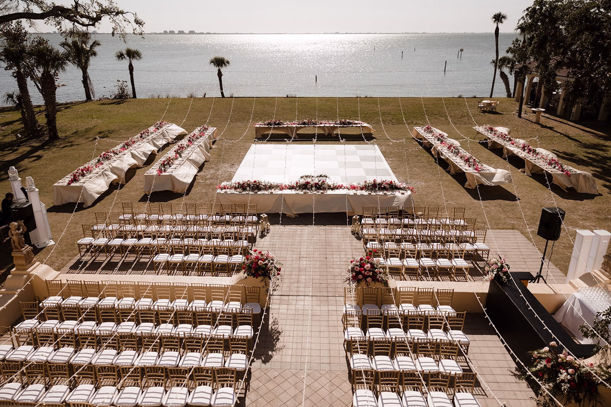 54Romantic Pink and Gold Waterfront Florida Wedding Sarasota Venue Powel Crosley Estate - Vibrant Pink and Gold Multicultural Sarasota Wedding | Powel Crosley Estate Garden Romantic Outdoor Wedding Reception | Lush Full-Length Floral Centerpieces Arrangements with Pink, Red and Blush Roses, Hydrangeas and Greenery Reception Decor Inspiration | String Lights and Gold Chairs Reception Ceremony Decor Ideas | Black and White Checkered Dance Floor Inspiration | Tampa Bay Wedding Photographer Evoke Photo and Film | Sarasota Wedding Venue Powel Crosley Estate