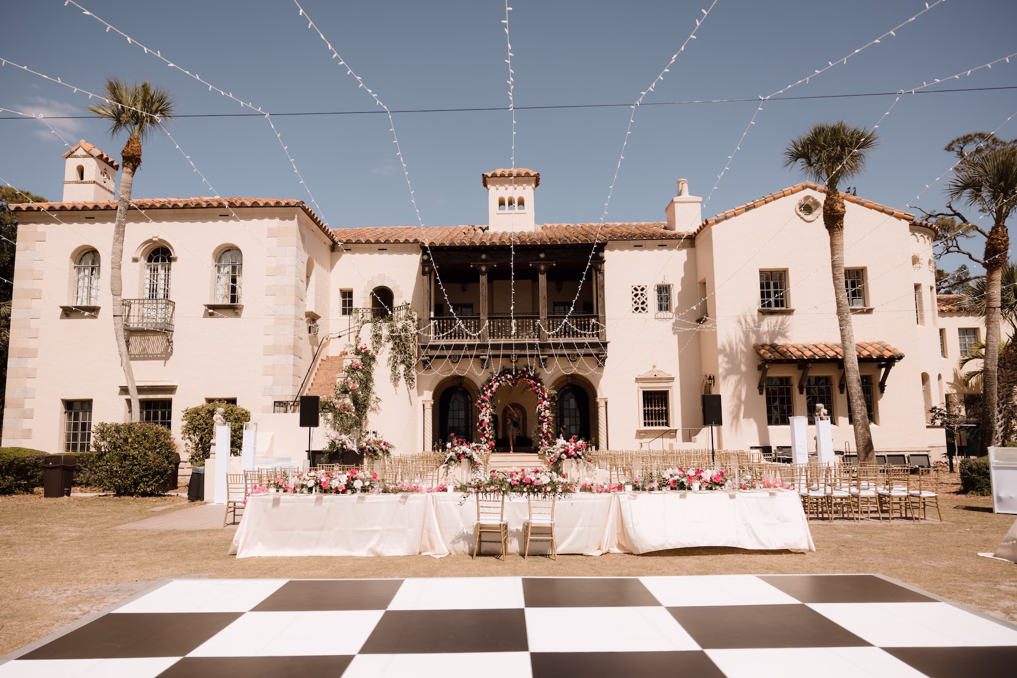 67Romantic Pink and Gold Waterfront Florida Wedding Sarasota Venue Powel Crosley Estate - Vibrant Pink and Gold Multicultural Sarasota Wedding | Powel Crosley Estate Garden Romantic Outdoor Wedding Reception | Lush Long Feasting Table with Pink, Red and Blush Roses, Hydrangeas and Greenery Garland Centerpiece Reception Decor Inspiration | Candlelight Tablescape Decor Ideas | String Lights and Candlelit Table Reception Decor Inspiration | Black and White Checkered Dance Floor Ideas | Sarasota Wedding Venue Powel Crosley Estate