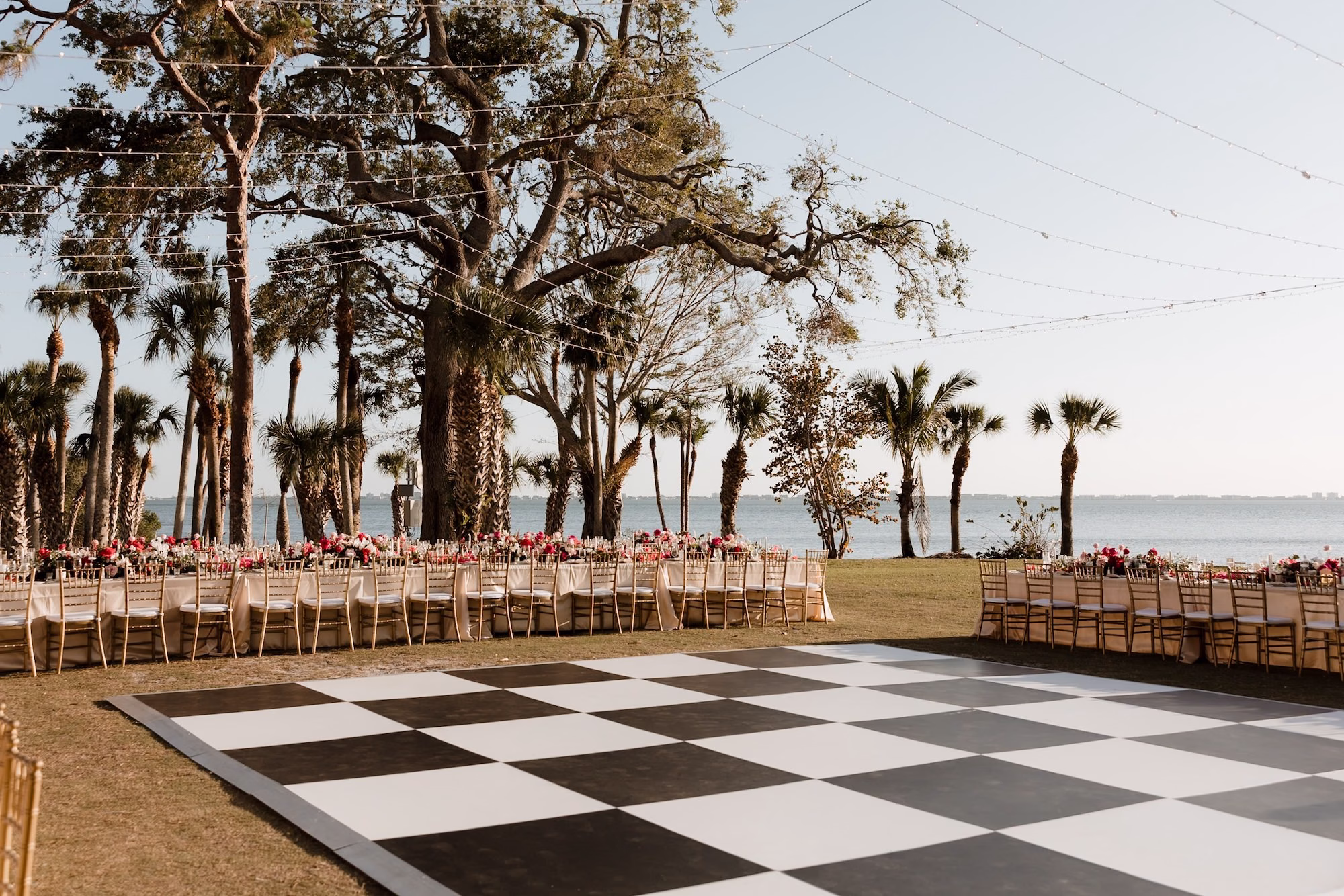 68Romantic Pink and Gold Waterfront Florida Wedding Sarasota Venue Powel Crosley Estate - Vibrant Pink and Gold Multicultural Sarasota Wedding | Powel Crosley Estate Garden Romantic Outdoor Wedding Reception | Lush Long Feasting Table with Pink, Red and Blush Roses, Hydrangeas and Greenery Garland Centerpiece Reception Decor Inspiration | Candlelight Tablescape Decor Ideas | String Lights and Candlelit Table Reception Decor Inspiration | Black and White Checkered Dance Floor Ideas | Sarasota Wedding Venue Powel Crosley Estate