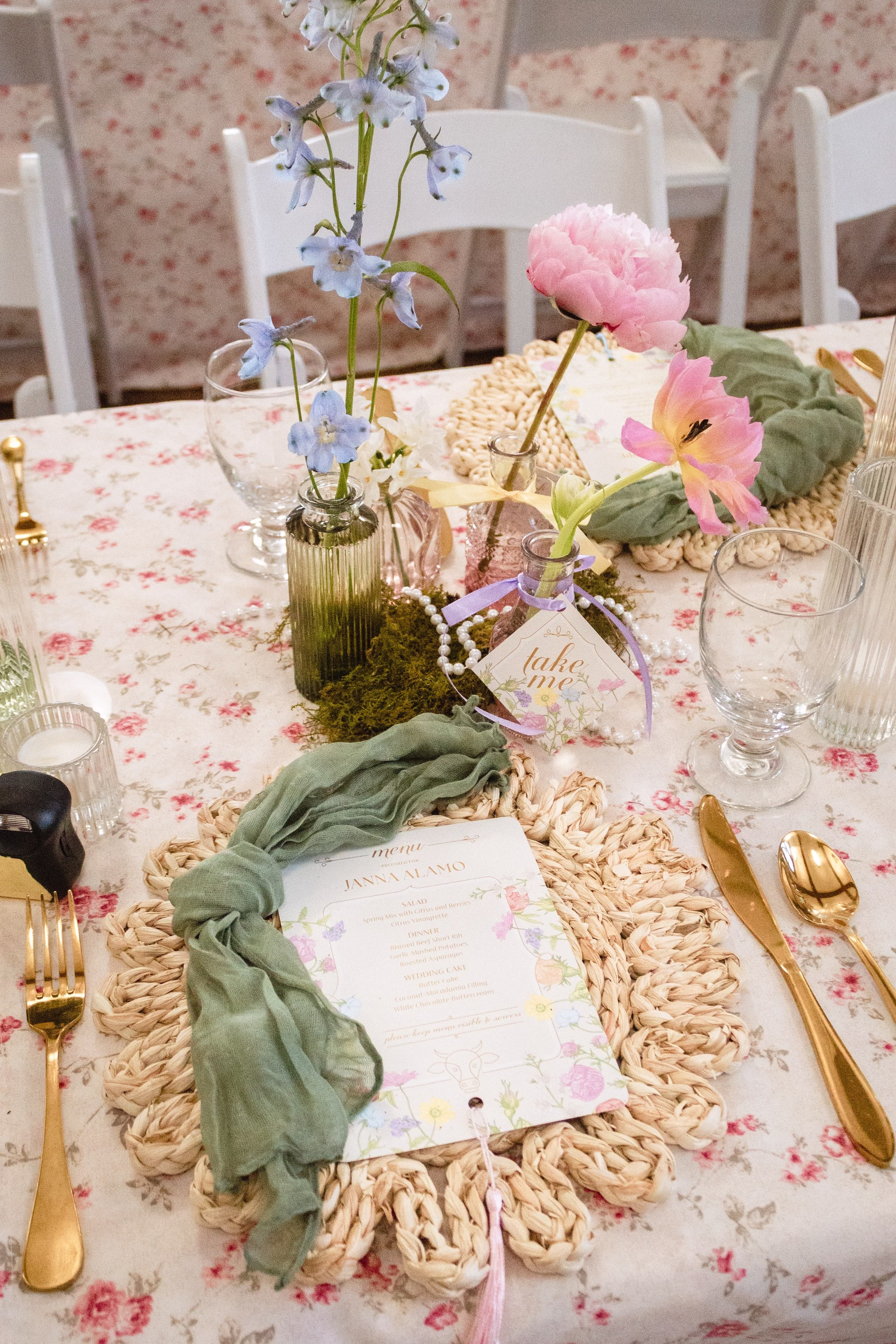 Romantic Ballroom Wedding Reception | Spring Pastel Garden Wedding Reception Decor Inspiration | Spring Floral Patterned Linens with Woven Scalloped Chargers, Olive Green Linen Napkins and Gold Flatware Tablescape Decor Ideas | Pink, White, Blush Roses, Orchids and Hydrangeas Flowers in Bud Vases Centerpiece Decor Inspiration