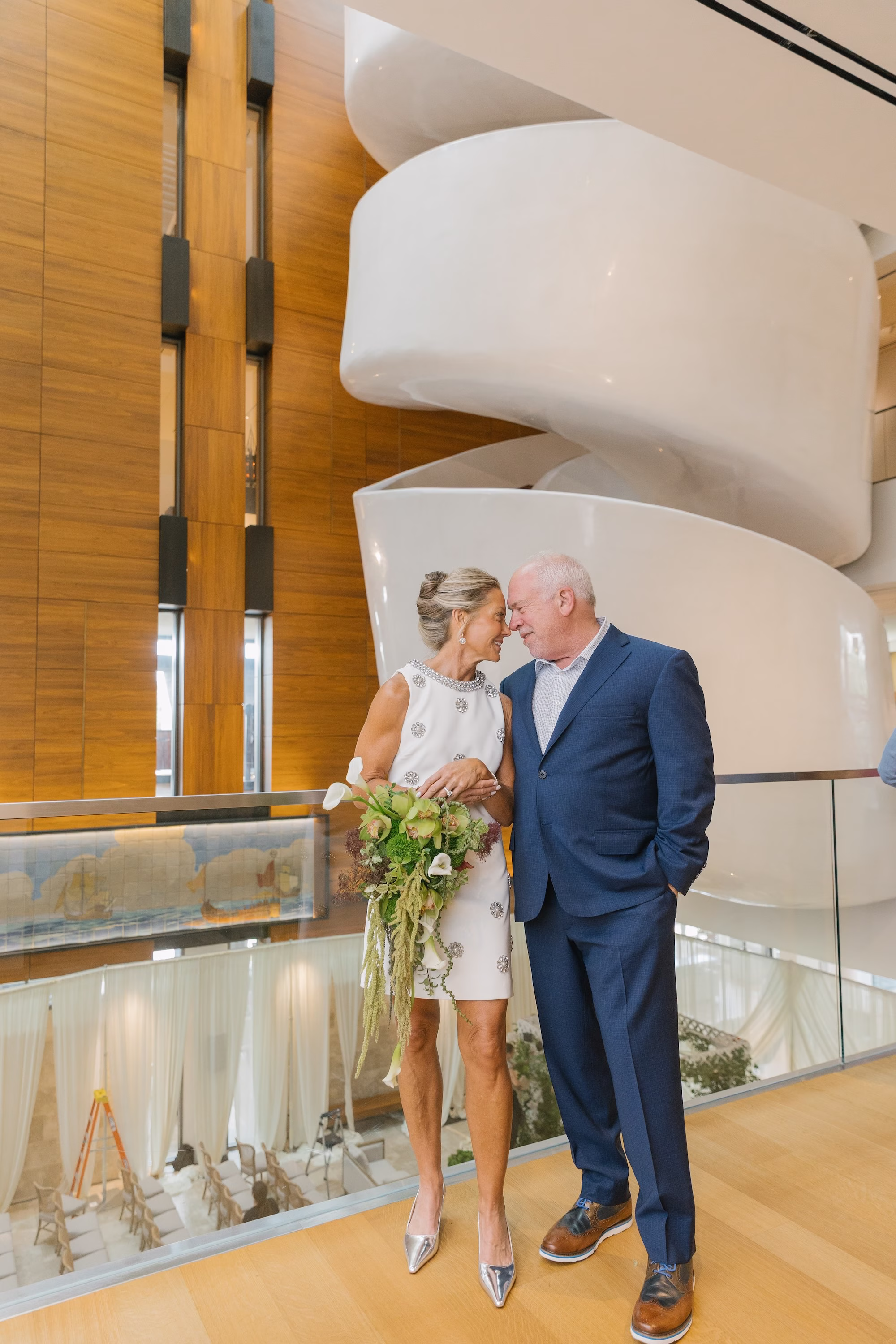 Bride and Groom Wedding Portrait in front of Staircase of Wedding Event Venue St Pete Event Venue Museum of the American Arts and Crafts Movement | Elegant White and Green Cascading Wedding Bridal Bouquet of Calla Lilies, Orchids, Amaranthus Inspiration | Modern Short Halter Style Neckline White Wedding Dress with Intricate 3D Floral Appliqués Ideas | Silver Manolo Blahnik Wedding Bridal Shoes Inspiration