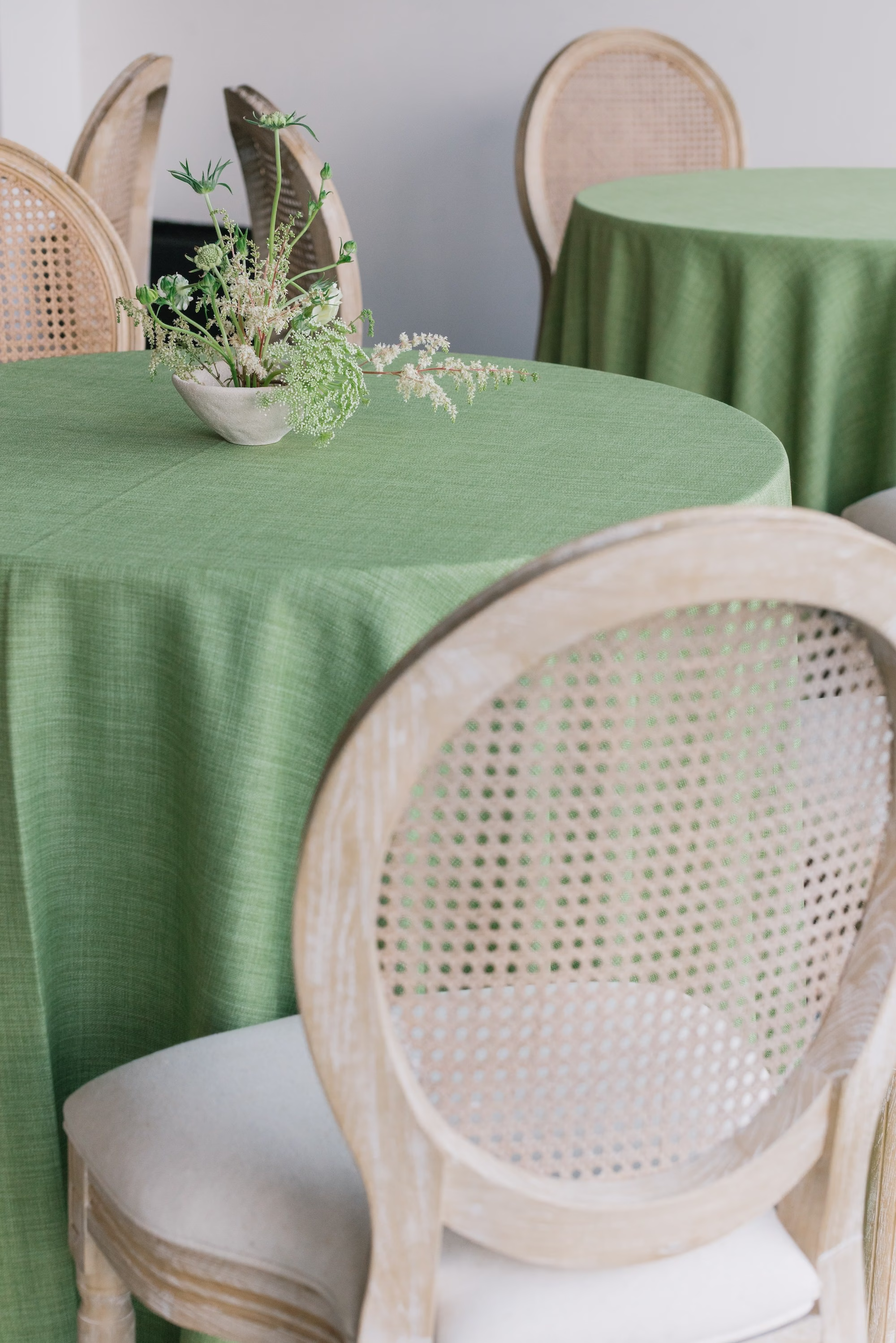 Elegant White and Green Wedding Reception Decor Inspiration | Light Green Table Linen with White Wooden Woven Cane Back Chairs Ideas | Simple Minimalistic Centerpiece with White Florals and Delicate Greenery Inspiration | St Pete Planner Stelloccasions Weddings and Events