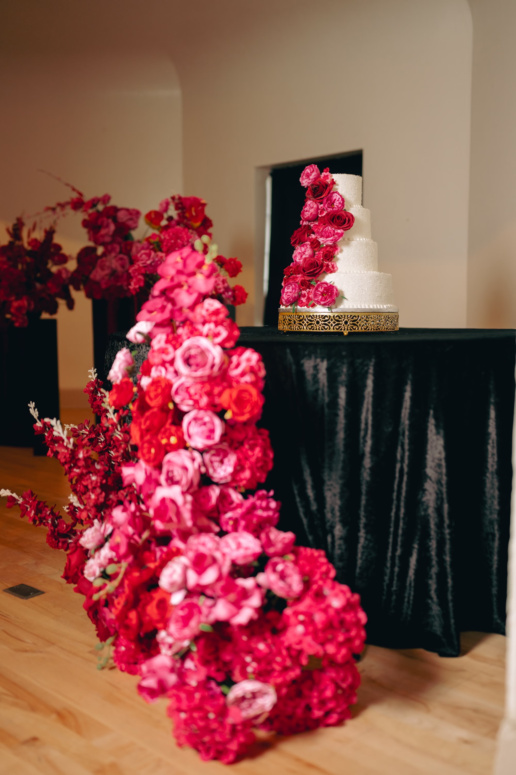 36Bold Pink Red and Burgundy Wedding Ideas - Glamorous, Burgundy Lakeland Wedding | Lake Mirror Amphitheater Four Tier White Wedding Cake on Gold Cake Stand and Black Velvet Linens with Red, Pink, Burgundy Cascading Florals Inspiration | Cascading Floral Arrangement of Red, Hot Pink and Burgundy Roses, Orchids and Hydrangeas Ideas