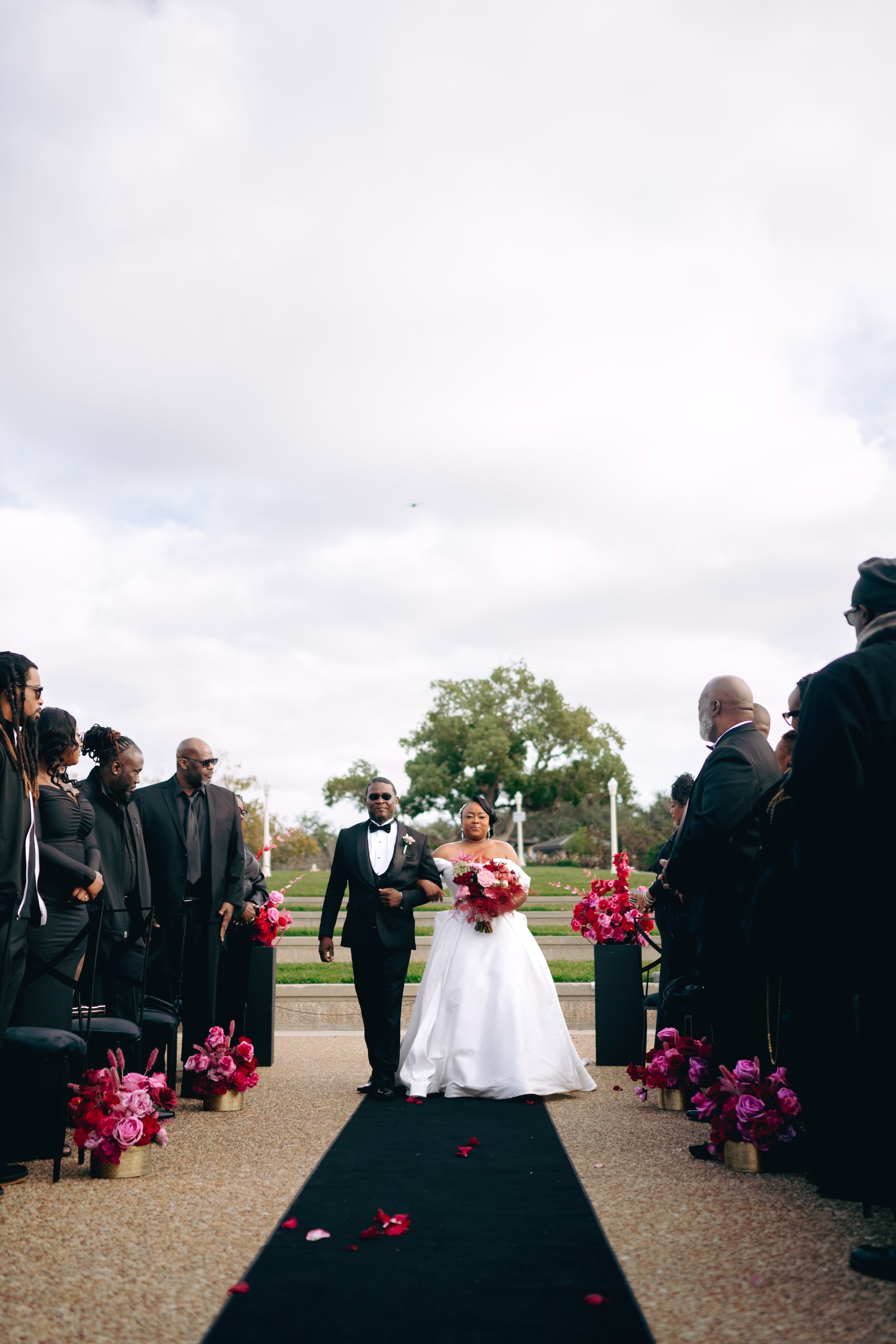 8Bold Pink Red and Burgundy Wedding Ideas - Glamorous, Burgundy Lakeland Wedding | Lake Mirror Amphitheater Bride and Father Walking Down Wedding Ceremony Aisle | Pink, Red, Burgundy Wedding Ceremony Floral Decor Ideas | Black Aisle Runner Wedding Ceremony Decor Inspiration | Lakeland Wedding Ceremony Venue Lake Mirror Amphitheater