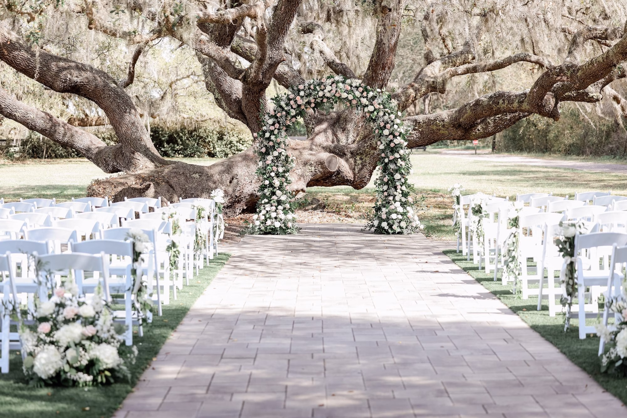 Spring Garden Outdoor Florida Wedding Inspiration | Whimsical Floral Altar Arch of White, Blush Roses and Greenery Wedding Ceremony Decor Ideas | White Garden Lawn Folding Wedding Ceremony Chairs Inspiration | Tampa Bay Event Venue Legacy Lane Weddings