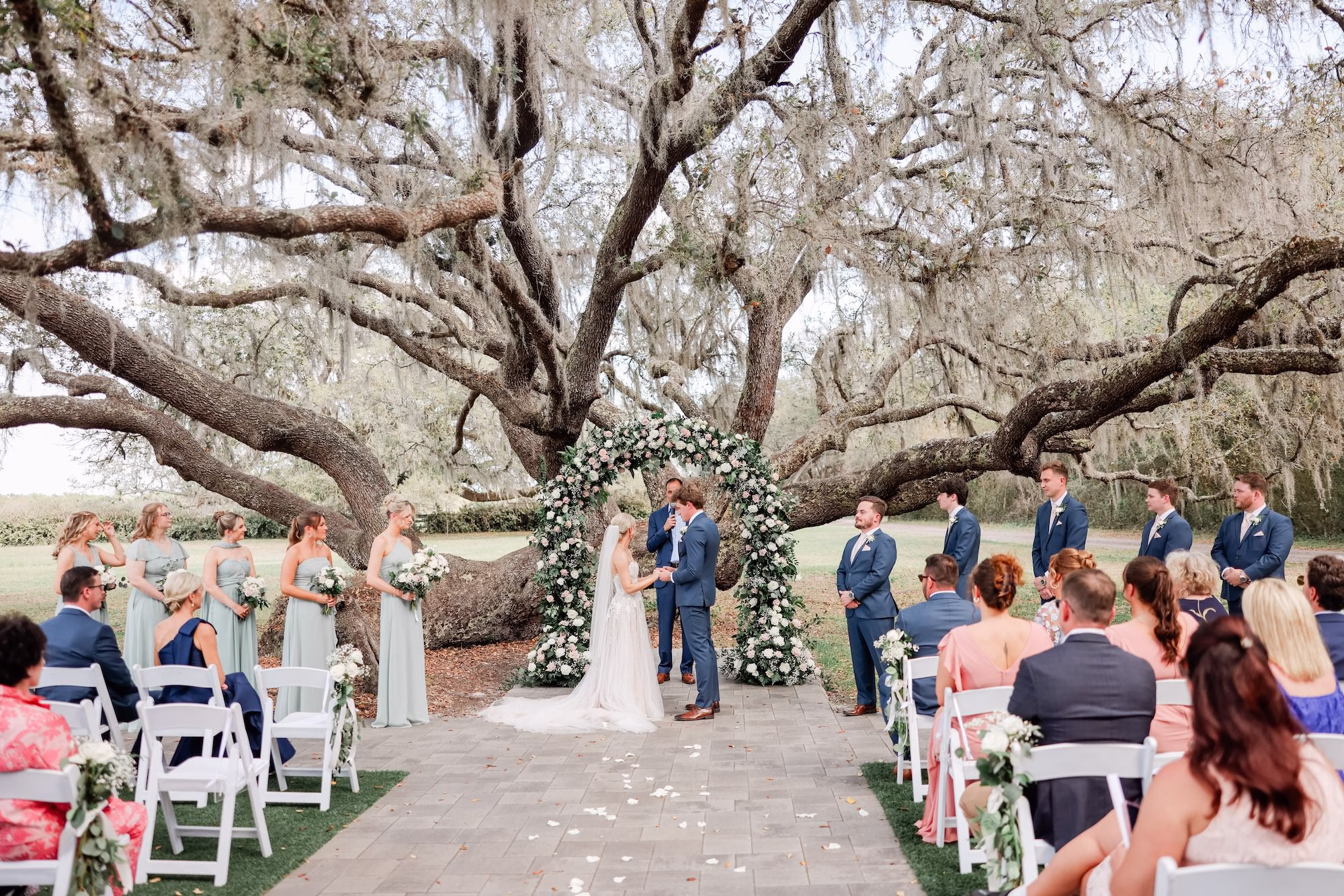 Bride and Groom Wedding Ceremony Vow Exchange Wedding Portrait | Spring Garden Outdoor Florida Wedding Inspiration | Whimsical Floral Altar Arch of White, Blush Roses and Greenery Wedding Ceremony Decor Ideas | Clearwater Photographer Lifelong Photography Studio | Tampa Bay Event Venue Legacy Lane Weddings