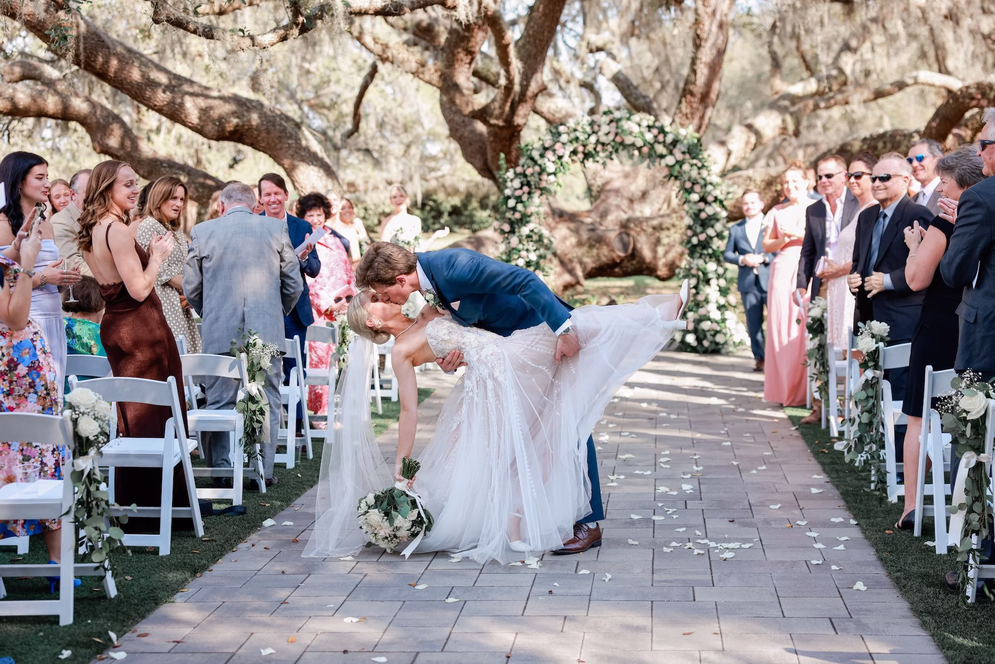 Bride and Groom Wedding Ceremony Aisle Just Married Kiss Wedding Portrait | Spring Garden Outdoor Florida Wedding Inspiration | Whimsical Floral Altar Arch of White, Blush Roses and Greenery Wedding Ceremony Decor Ideas | Clearwater Photographer Lifelong Photography Studio | Tampa Bay Event Venue Legacy Lane Weddings