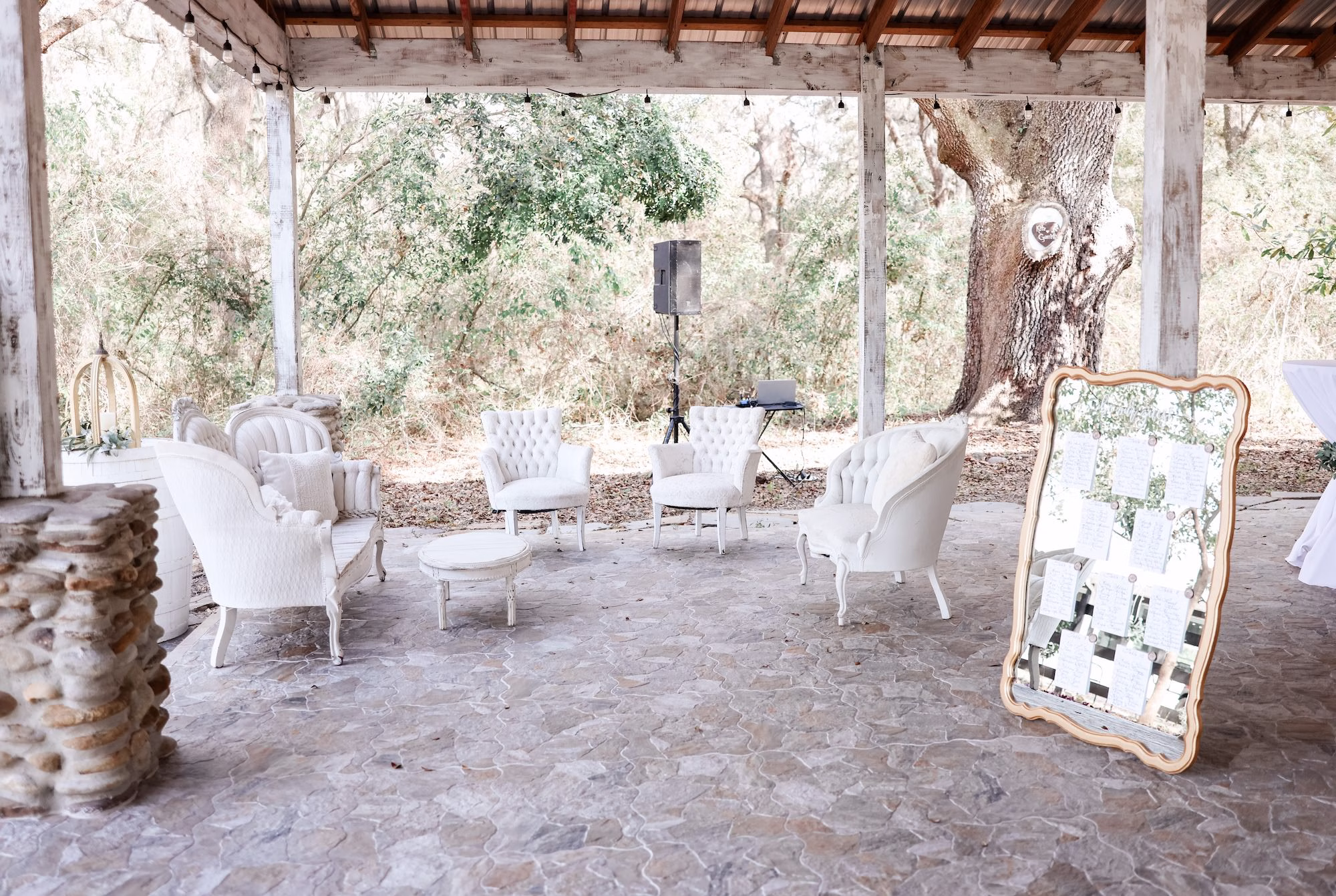 Outdoor Wedding Reception Cocktail Lounge in Rustic Wooden Pavilion Inspiration | Vintage White Tufted Loveseats Seating Decor Ideas | Ornate Vintage Gold Mirror Wedding Reception Seating Chart Decor Inspiration | Tampa Bay Event Venue Legacy Lane Weddings