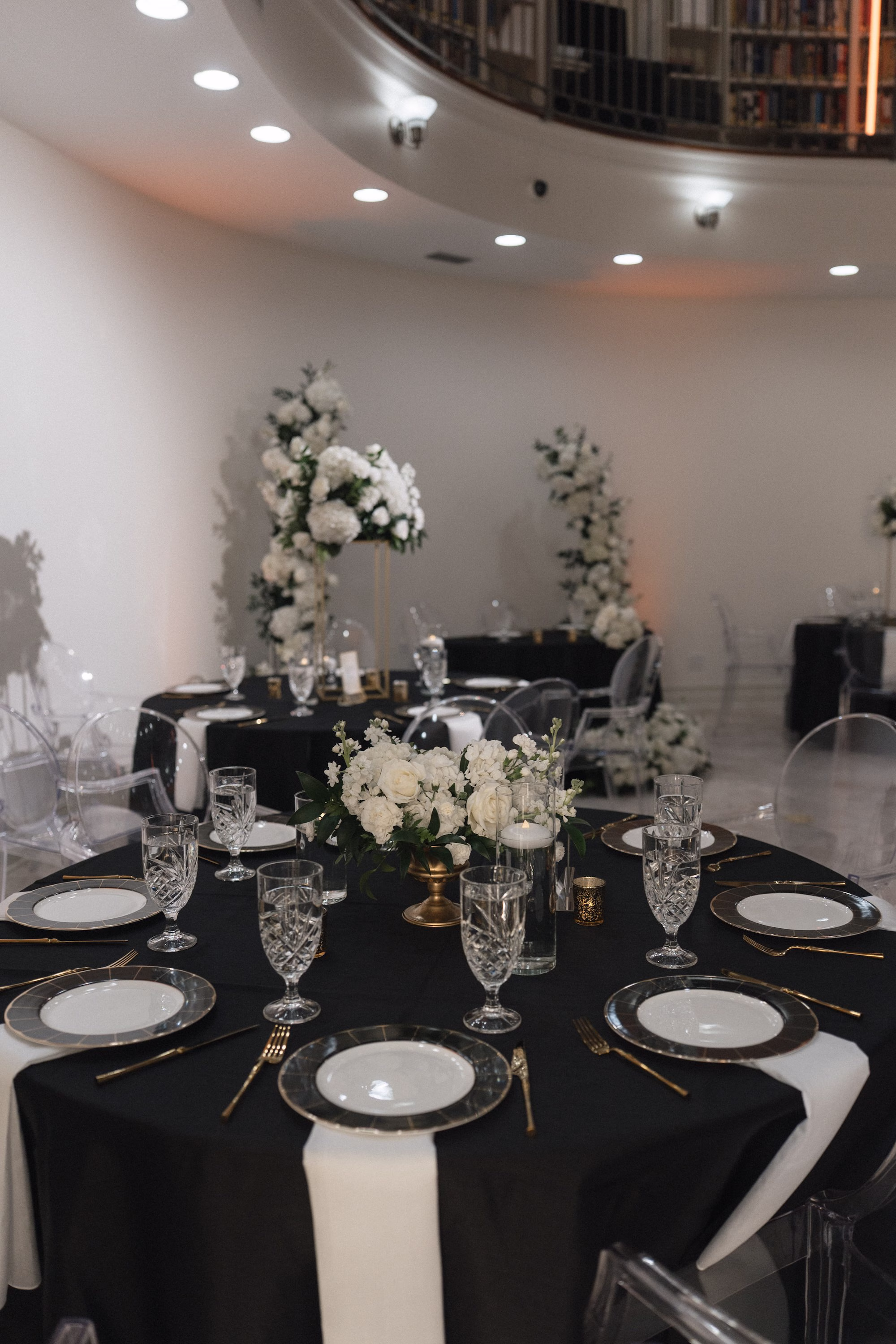 38Timeless Black and Wedding New Years Eve Wedding Ideas - Timeless Black and White Tarpon Springs Wedding | Whitehurst Gallery Timeless White and Black New Years Eve Ballroom Wedding Reception | Black Linens with Crystal Drinkware and Black and Gold Chargers with White Plate Tablescape Decor Inspiration | Monochromatic White Floral Centerpiece with Floating Tea Candles Decor Ideas