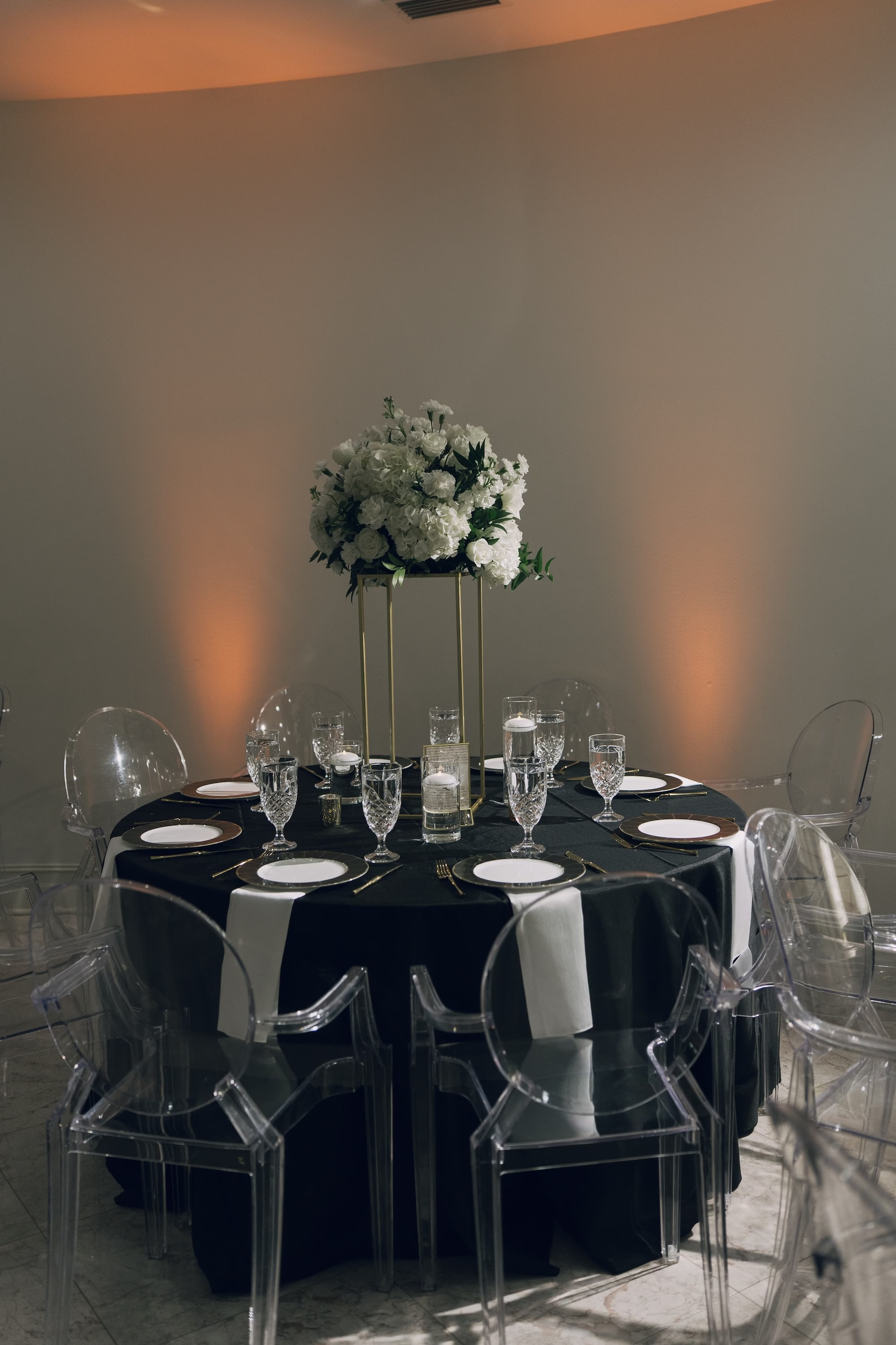 39Timeless Black and Wedding New Years Eve Wedding Ideas - Timeless Black and White Tarpon Springs Wedding | Whitehurst Gallery Timeless White and Black New Years Eve Ballroom Wedding Reception | Black Linens with Crystal Drinkware and Black and Gold Chargers with White Plate Tablescape Decor Inspiration | Acrylic Ghost Chairs Ideas | Tall Monochromatic White Floral Centerpiece on Gold Stand Inspiration