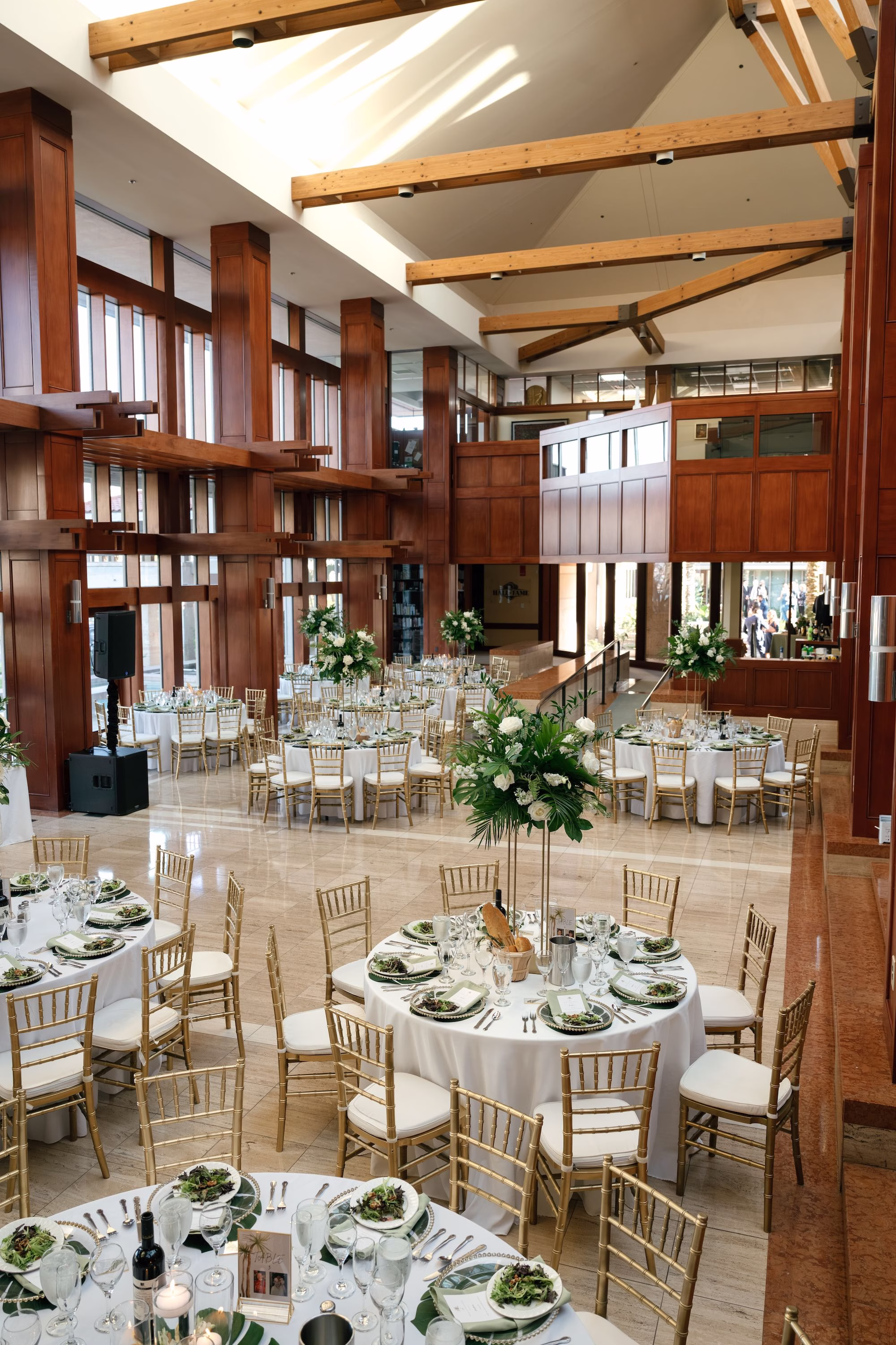 39Tropical Green Florida Wedding Ideas St Pete Venue Poytner Institute - Tropical, Green Downtown St. Pete Wedding | Poynter Institute Tropical Green and White Luxurious Ballroom Wedding Reception | Modern Gold Chiavari Chairs | Tall Gold Platform Centerpieces with White Florals and Greenery Arrangement Ideas | White Linens with Green Palm Chargers and Light Green Napkins Tablescape Decor Inspiration | St Pete Event Planner Coastal Coordinating | Florida Venue Poynter Institute
