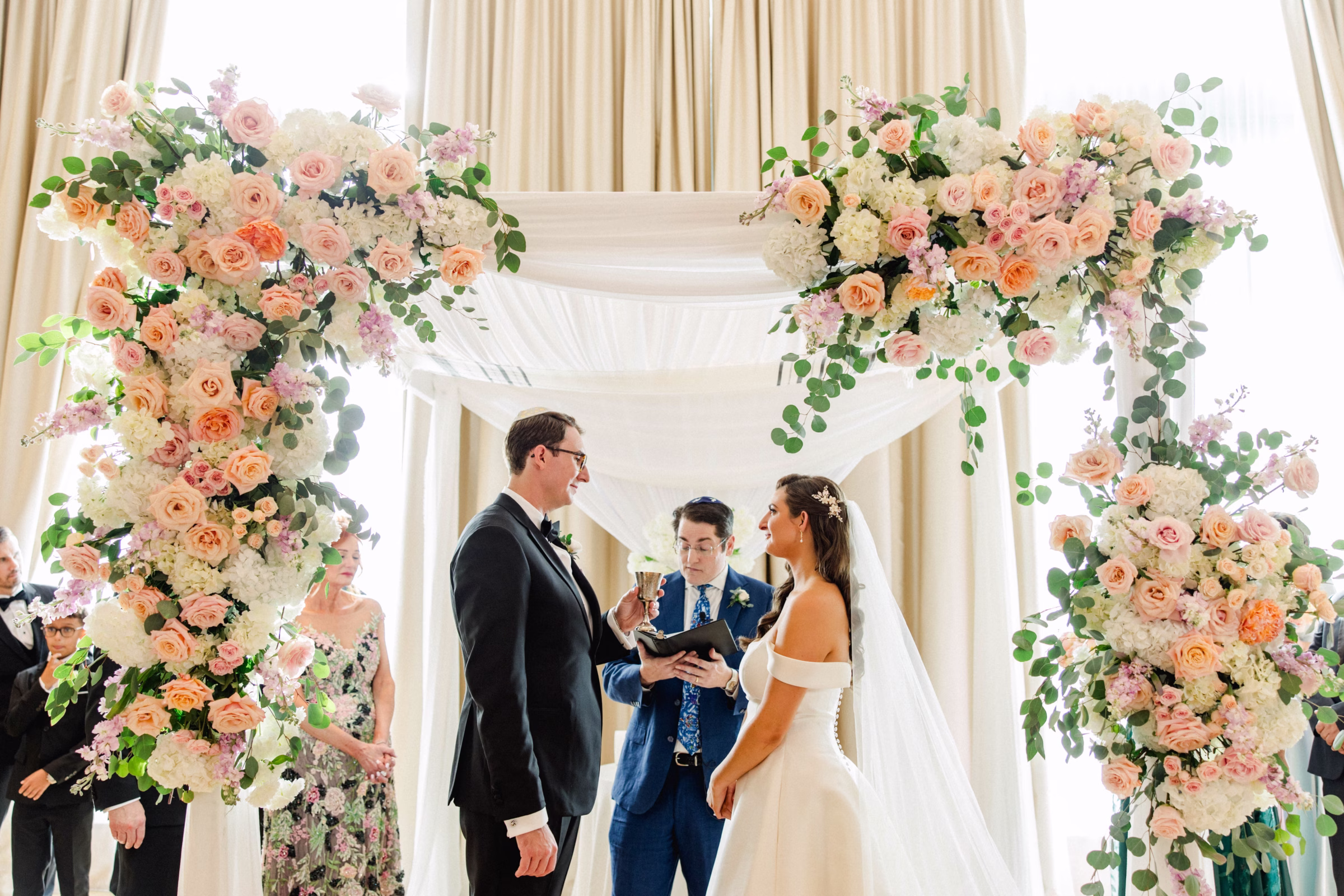 Bride and Groom Wedding Ceremony Vow Exchange Wedding Portrait | Spring Pastel Roses, Hydrangeas Blush, Peach, Cream, White Wedding Ceremony Floral Arrangement Decor Inspiration | White Draping and Spring Floral Decor on Wedding Chuppah Jewish Wedding Ceremony Decor Ideas | Downtown Event Venue The Edition Hotel Tampa