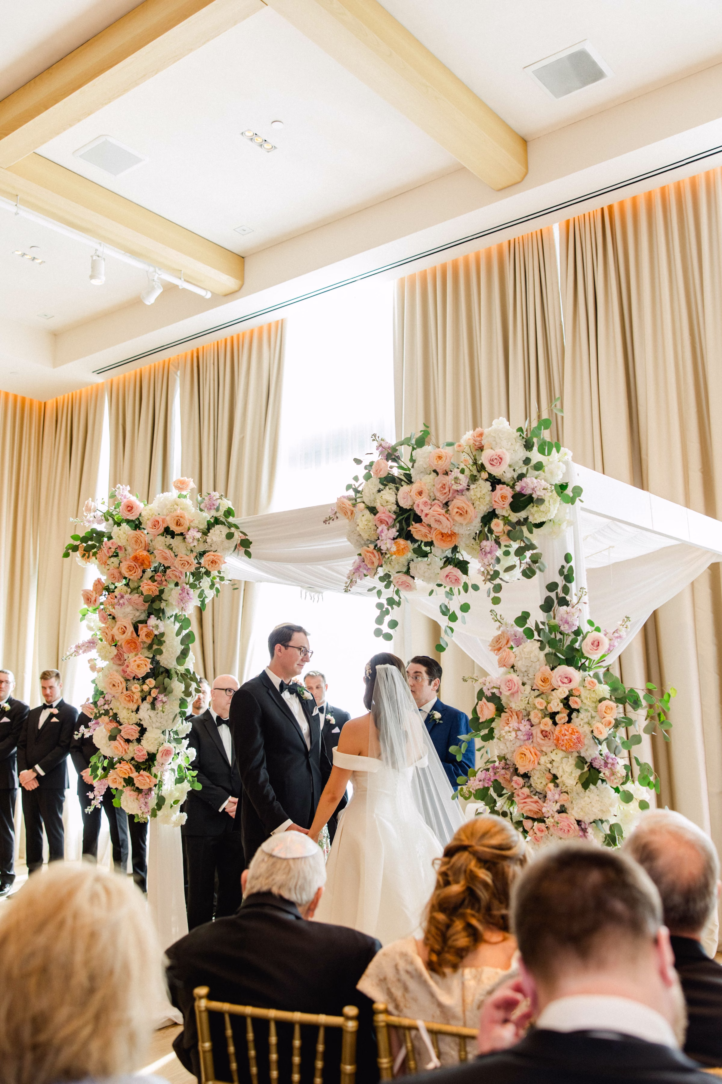 Bride and Groom Wedding Ceremony Vow Exchange Wedding Portrait | Spring Pastel Roses, Hydrangeas Blush, Peach, Cream, White Wedding Ceremony Floral Arrangement Decor Inspiration | White Draping and Spring Floral Decor on Wedding Chuppah Jewish Wedding Ceremony Decor Ideas | Downtown Event Venue The Edition Hotel Tampa