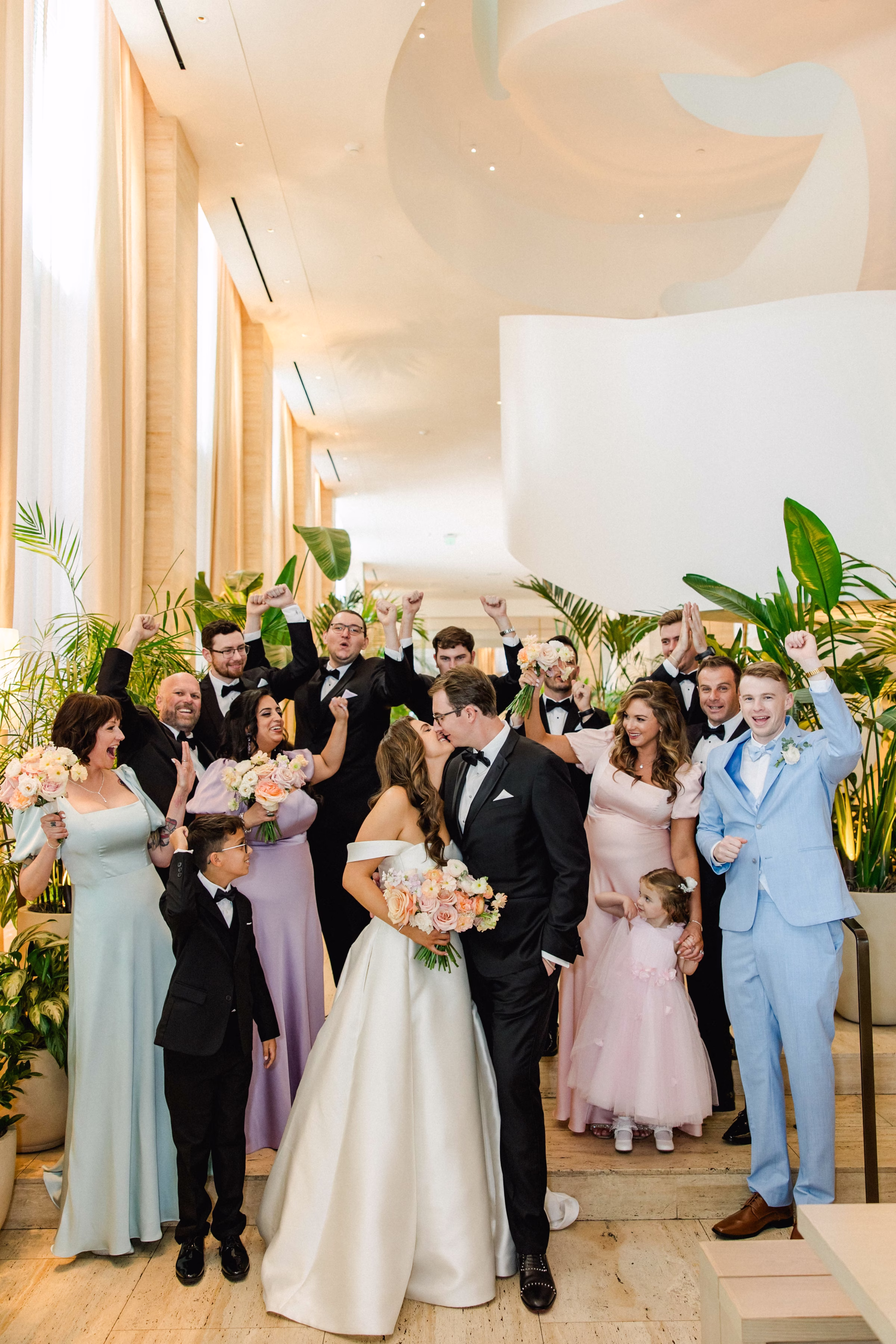 Bride and Groom Kiss with Bridal Party Wedding Portrait | Pastel Spring Colors Purple, Blue and Pink Bridesmaid Dress Ideas