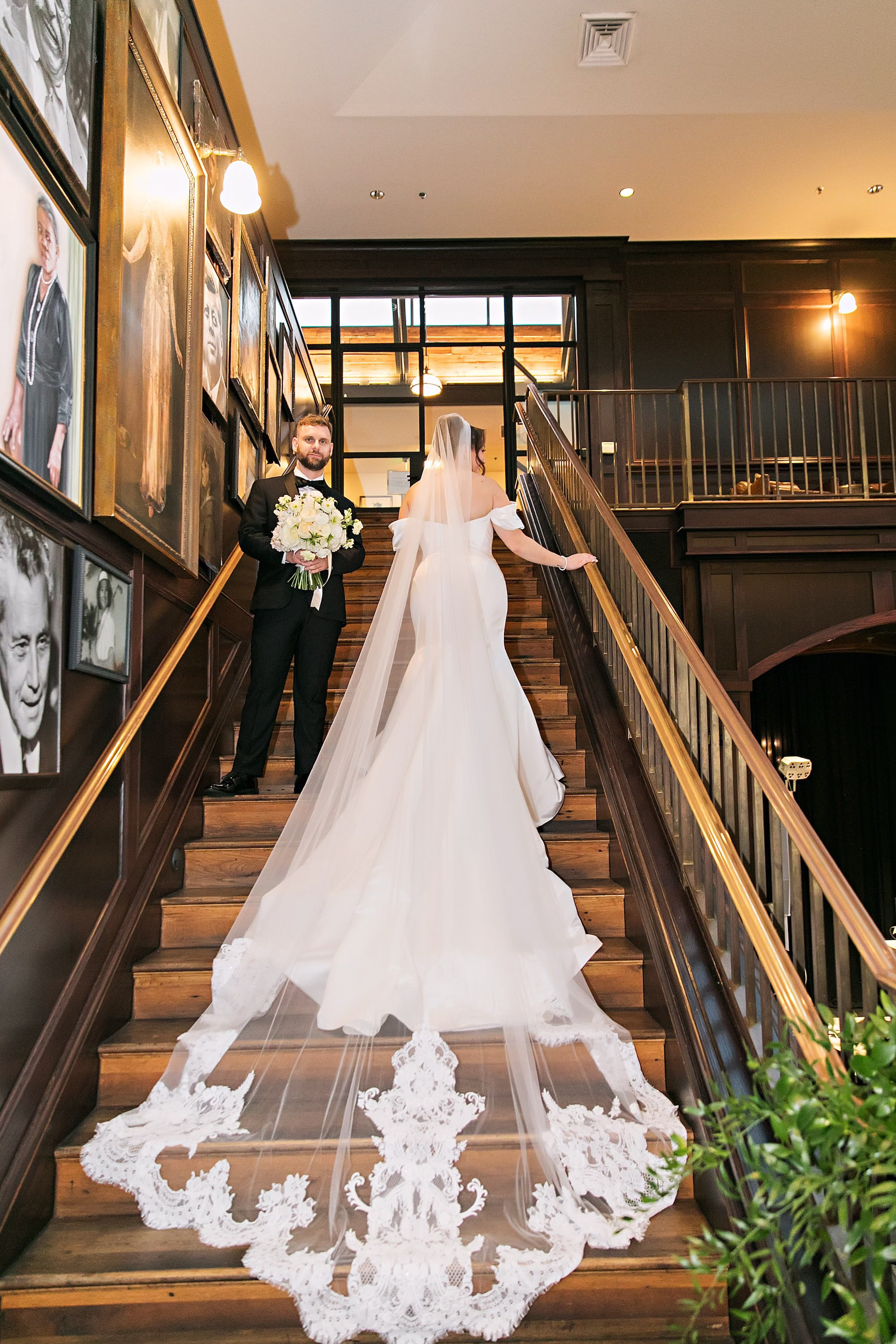 Bride and Groom Wedding Portrait on Grand Staircase in South Tampa Wedding Venue Oxford Exchange | Chich Historic Wedding Venue Inspiration | Off the Shoulder White Fit and Flare Wedding Gown with Dramatic Cathedral Length Lace Bordered Veil Inspiration | Tampa Bay Photographer Limelight Photography
