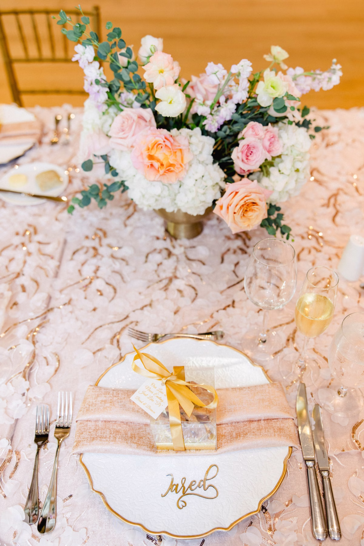 Romantic Pastel Blush Spring Garden Wedding Reception Tablescape Decor Inspiration | White Charger with Gold Rim and Gold Nameplate Decor Ideas | Spring Florals Roses, Hydrangeas, Carnations, Peonies Pastel Peach, Blush, Cream, White Flower Centerpiece Arrangement Inspiration