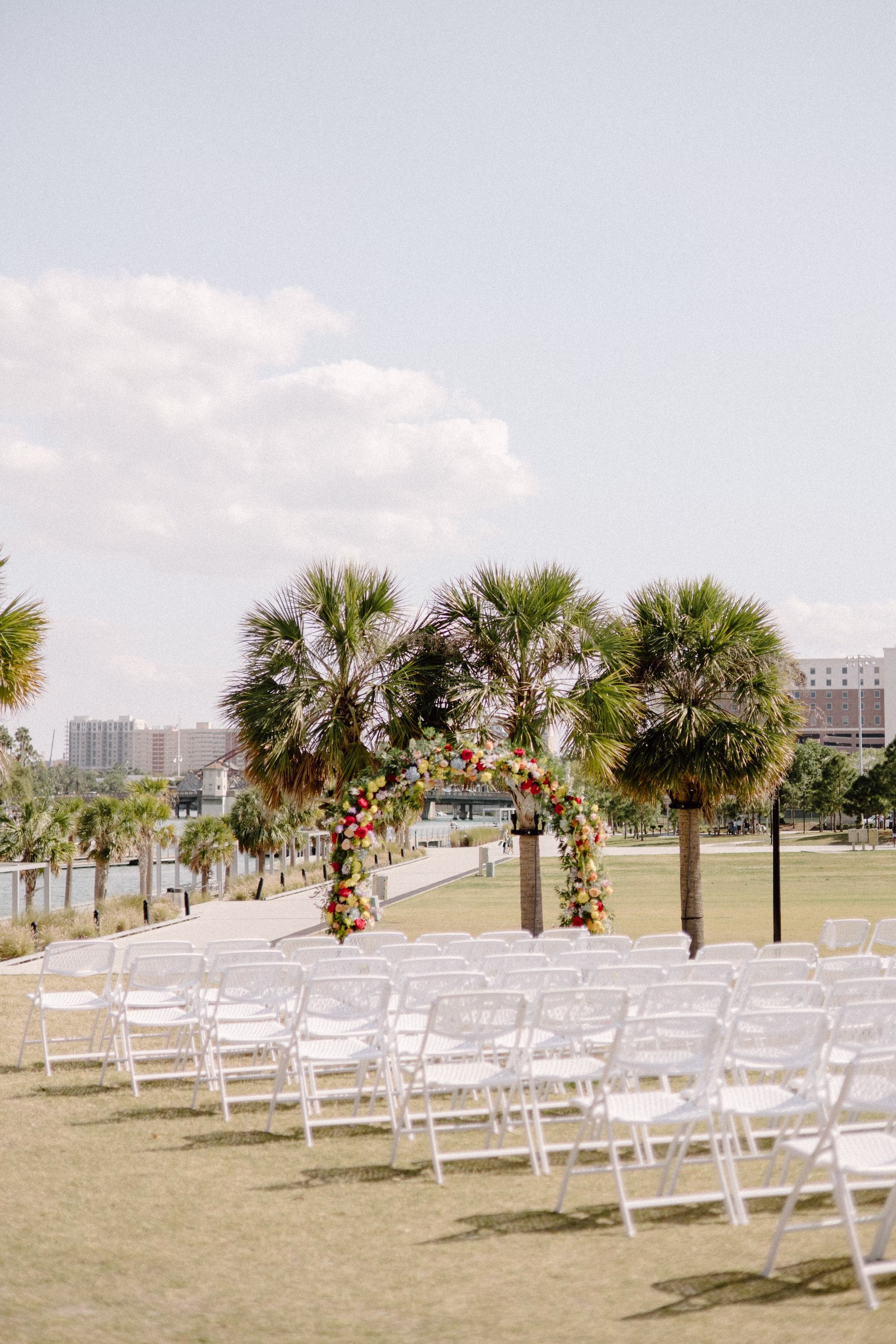 15Whimsical Pastel Spring Orange Yellow and Purple Wedding Inspiration Venue Tampa River Center - Whimsical, Colorful Waterfront Wedding | Tampa River Center Colorful Spring Garden Riverfront Wedding Ceremony Inspiration | White Garden Ceremony Chairs | Rounded Floral Wedding Ceremony Altar Arch with Spring Pastel Orange, Yellow, Lavender, Blush Floral Ideas | Planner Wilder Mind Events | Venue Tampa River Center