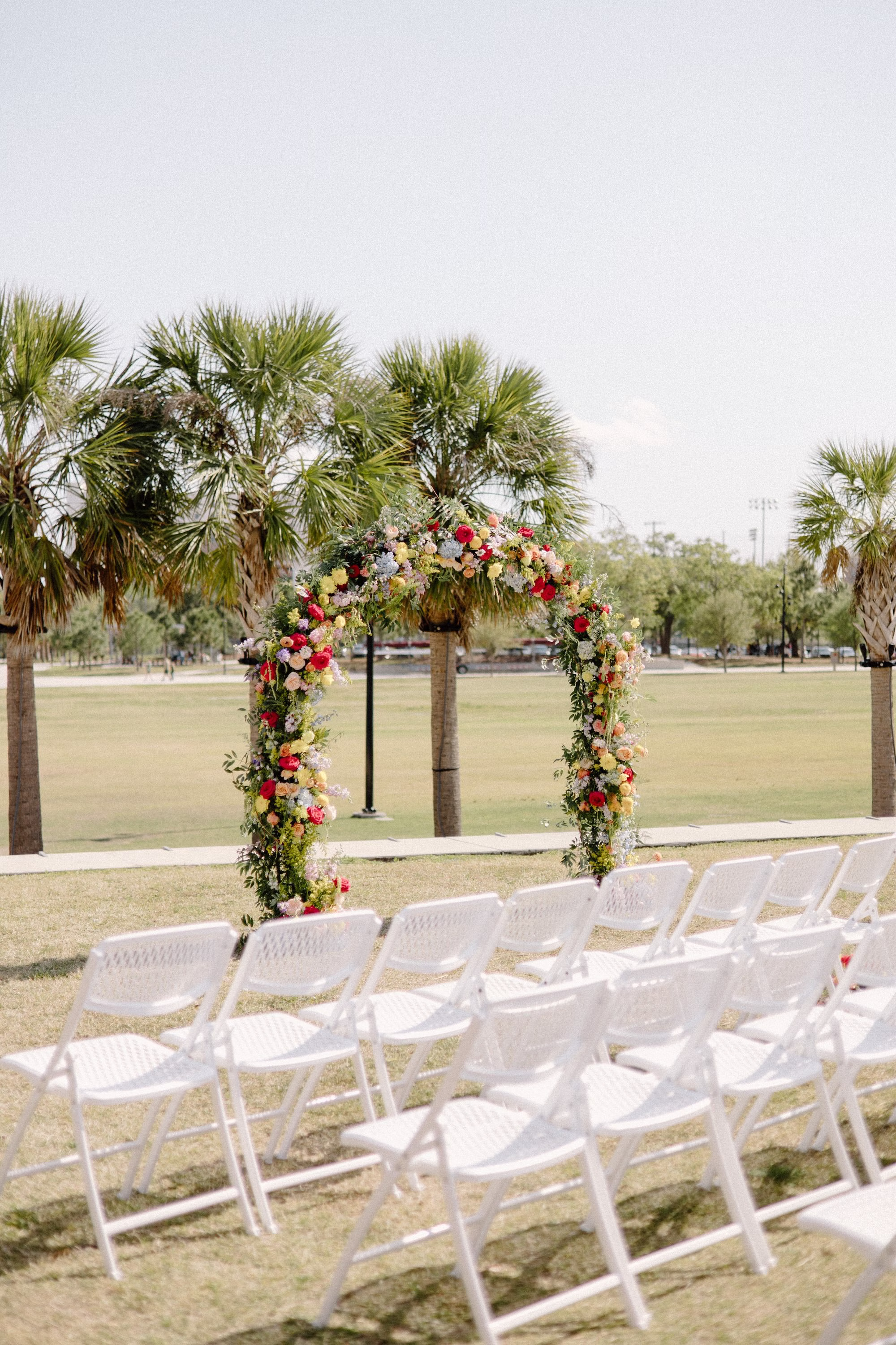 21Whimsical Pastel Spring Orange Yellow and Purple Wedding Inspiration - Whimsical, Colorful Waterfront Wedding | Tampa River Center Colorful Spring Garden Riverfront Wedding Ceremony Inspiration | White Garden Ceremony Chairs | Rounded Floral Wedding Ceremony Altar Arch with Spring Pastel Orange, Yellow, Lavender, Blush Floral Ideas | Planner Wilder Mind Events | Venue Tampa River Center