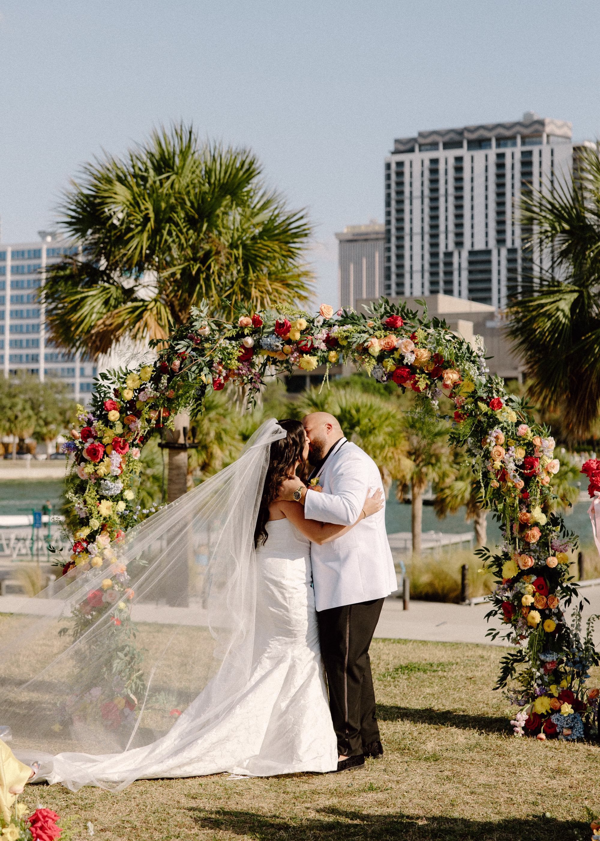 28Whimsical Pastel Spring Orange Yellow and Purple Wedding Inspiration - Whimsical, Colorful Waterfront Wedding | Tampa River Center Bride and Groom Wedding Ceremony Just Married Kiss Wedding Portrait | Colorful Spring Garden Riverfront Wedding Ceremony Inspiration | Rounded Floral Wedding Ceremony Altar Arch with Spring Pastel Orange, Yellow, Lavender, Blush Floral Ideas | Planner Wilder Mind Events | Clearwater Officiant Laurie Chandler Celebrant