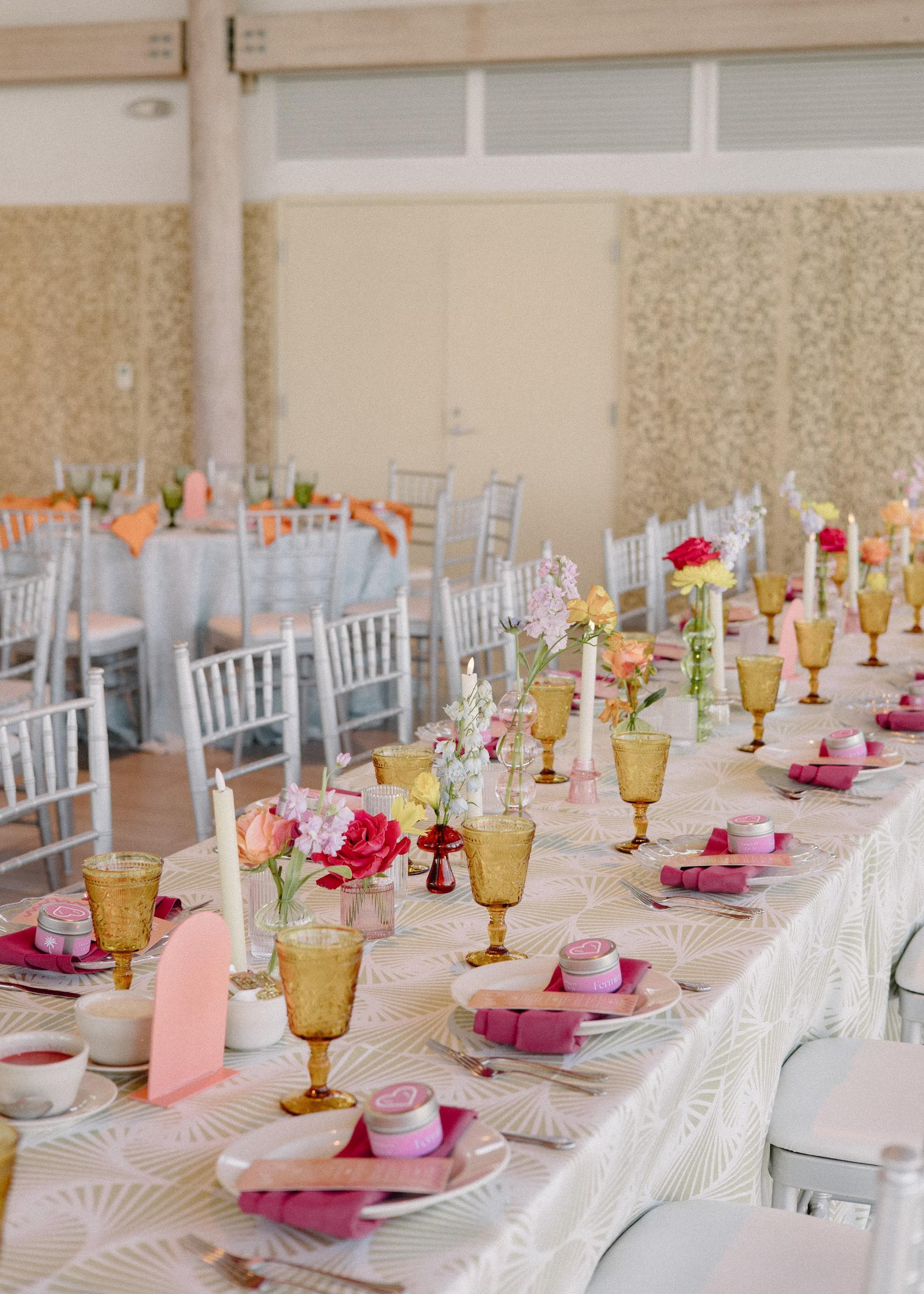 45Whimsical Pastel Spring Orange Yellow and Purple Wedding Inspiration - Whimsical, Colorful Waterfront Wedding | Tampa River Center White Chiavari Chairs with Textured Linens Decor Inspiration | Colored Depression Glassware with Bright Pink Napkins Tablescape Reception Decor Ideas | Single Pastel Floral Stems in Bud Vases Centerpiece Inspiration | Planner Wilder Mind Events