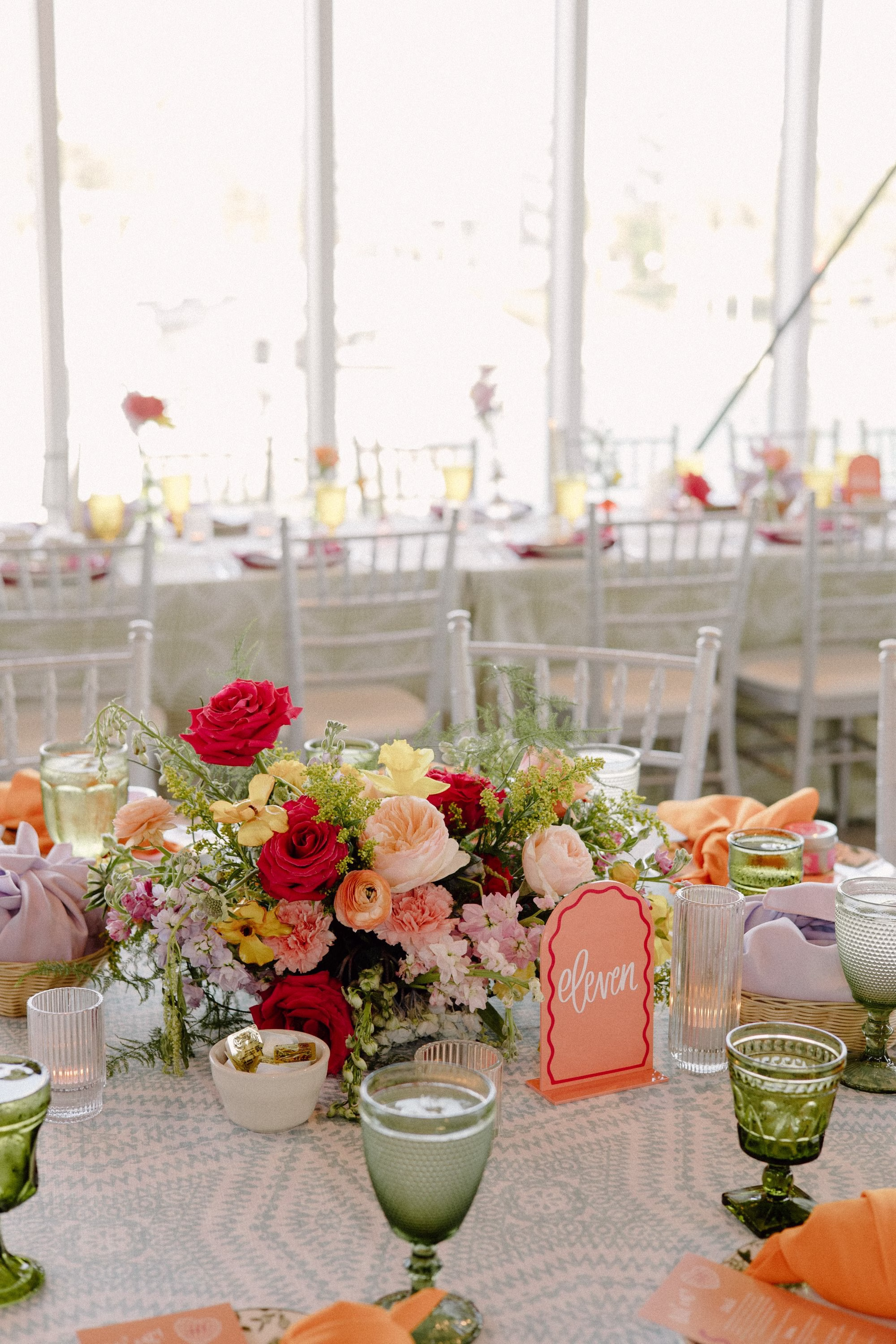 48Whimsical Pastel Spring Orange Yellow and Purple Wedding Inspiration - Whimsical, Colorful Waterfront Wedding | Tampa River Center White Chiavari Chairs with Textured Linens Decor Inspiration | Colored Depression Glassware with Bright Orange Napkins Tablescape Reception Decor Ideas | Lush Pastel Spring Centerpiece of Bright Pink, Orange, Yellow, Lilac, Blush, Baby Blue Florals Decor Inspiration | Orange and Red Modern Funky Table Number Ideas | Planner Wilder Mind Events