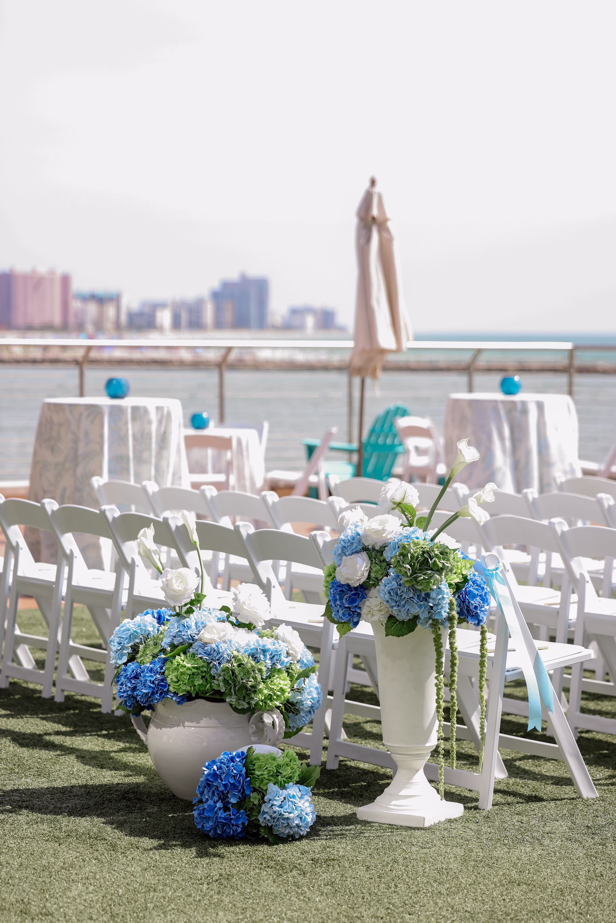 12Elegant Light Blue Coastal Florida Wedding Ideas - Elegant Blue Modern Coastal Wedding | Opal Sands Clearwater Beach Blue Hydrangea and White Rose Aisle Urns with White Folding Chairs and Clearwater Beach Skyline Wedding Ceremony Ideas