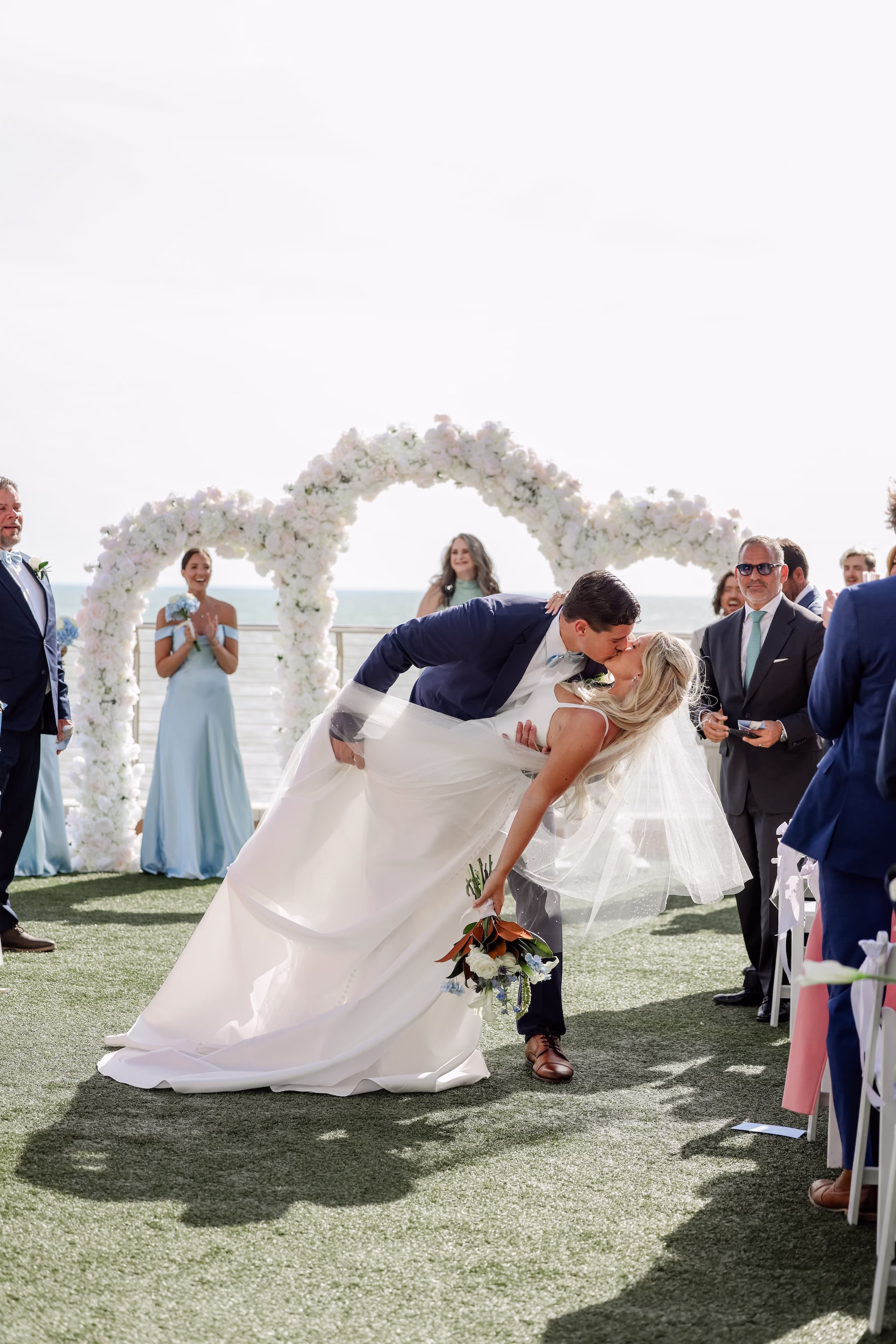 21Elegant Light Blue Coastal Florida Wedding Ideas - Elegant Blue Modern Coastal Wedding | Opal Sands Clearwater Beach Groom Dipping Bride for First Kiss Rooftop Beach Wedding Ceremony Portrait