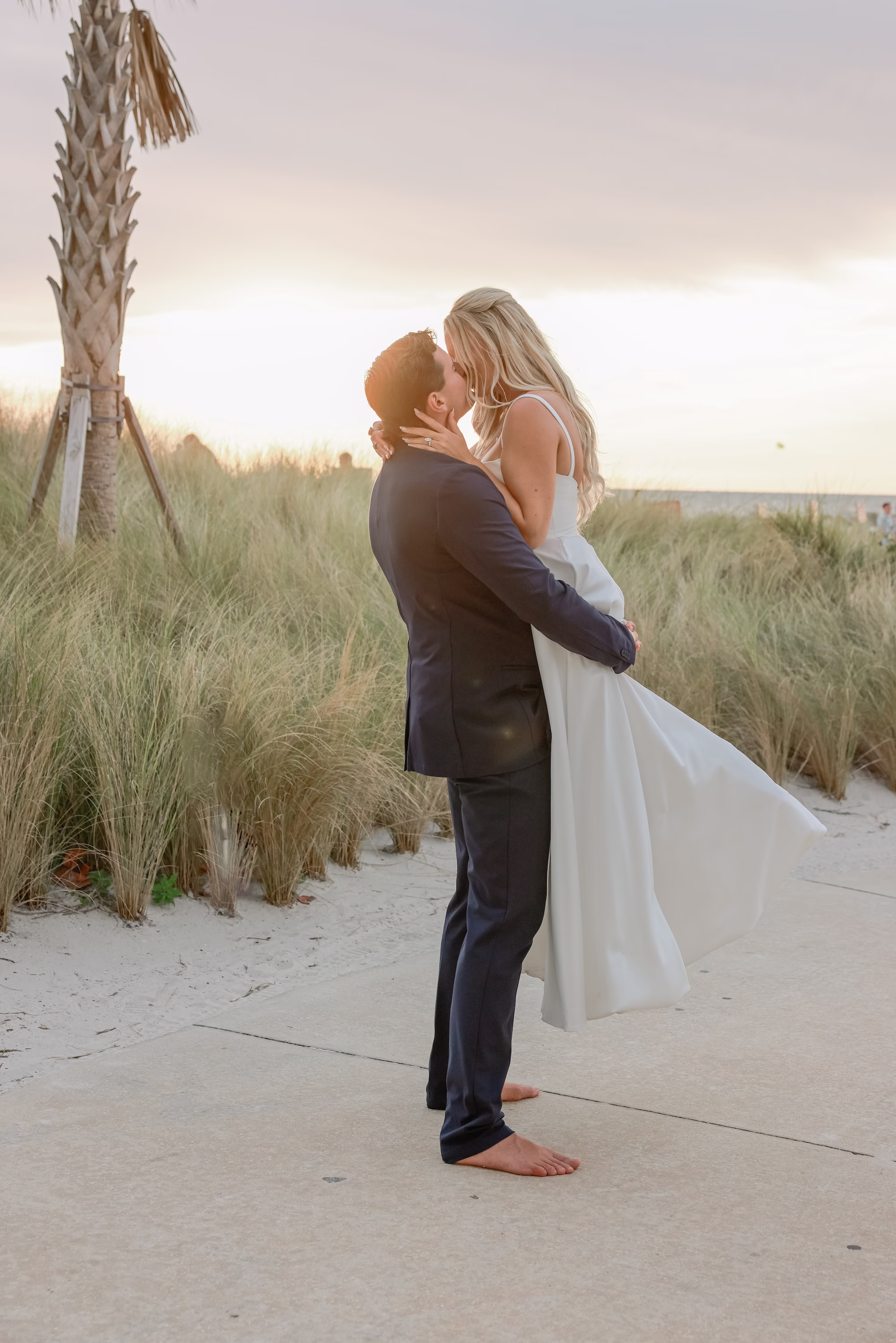 30Elegant Light Blue Coastal Florida Wedding Ideas - Elegant Blue Modern Coastal Wedding | Opal Sands Clearwater Beach Bride and Groom Kiss in Beach Dunes at Sunset Wedding Portrait with Barefoot Bride | Tampa Bay Photography Lifelong Photography Studio