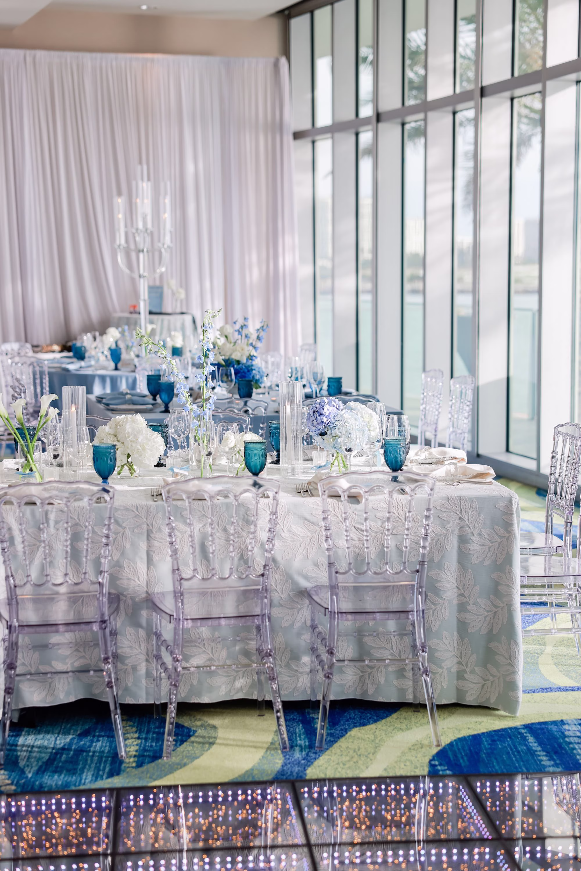 38Elegant Light Blue Coastal Florida Wedding Ideas - Elegant Blue Modern Coastal Wedding | Opal Sands Clearwater Beach Square Wedding Reception Table with Silver Damask Linen, Clear Chiavari Chairs and Blue Hydrangea Centerpiece by Floor-to-Ceiling Windows Ideas | Clearwater Beach Venue Opal Sands Resort | Gabro Event Rentals