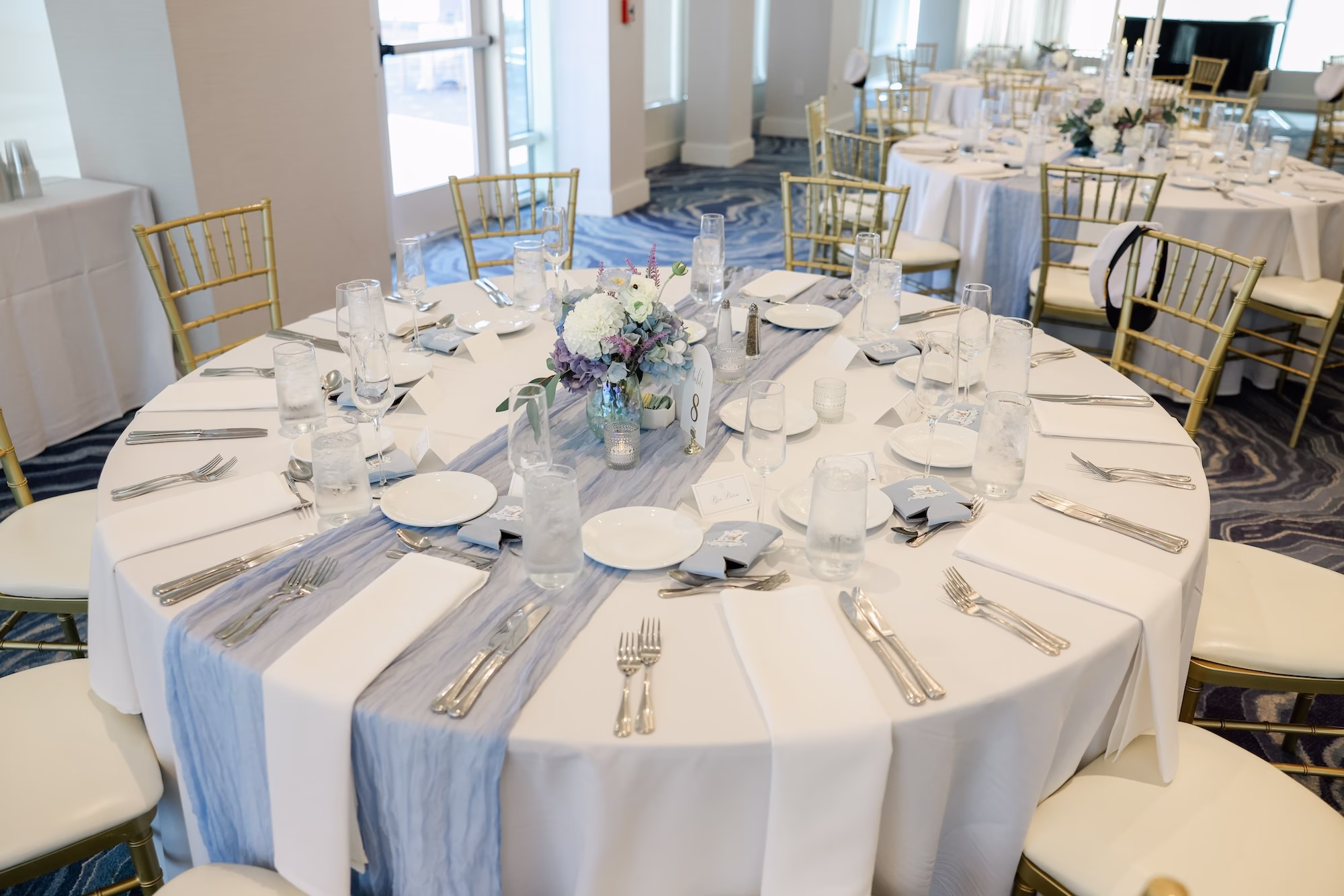 Luxurious Ballroom Coastal Wedding Reception | Modern Gold Chiavari Chairs | Romantic Lush Floral Centerpiece with White, Purple and Blue Hydrangeas and Roses Flower Arrangement Ideas | White Linens with Light Blue Chiffon Table Runner Tablescape Decor Inspiration | Wedding Venue Grand Hyatt Tampa Bay
