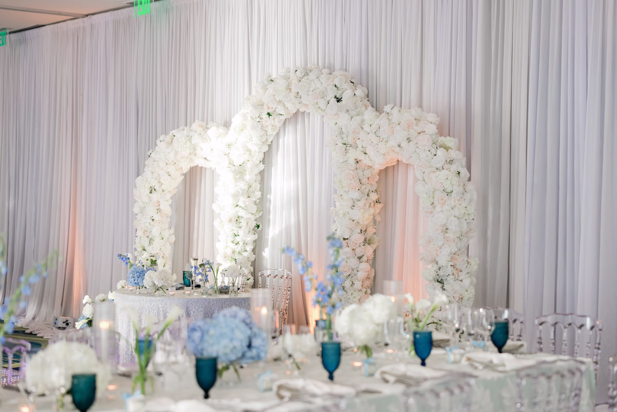 44Elegant Light Blue Coastal Florida Wedding Ideas - Elegant Blue Modern Coastal Wedding | Opal Sands Clearwater Beach Elegant Triple White Floral Arch Sweetheart Table Backdrop with White Draping and Blue Hydrangea Centerpieces Wedding Reception Ideas | Clearwater Beach Gabro Event Rentals