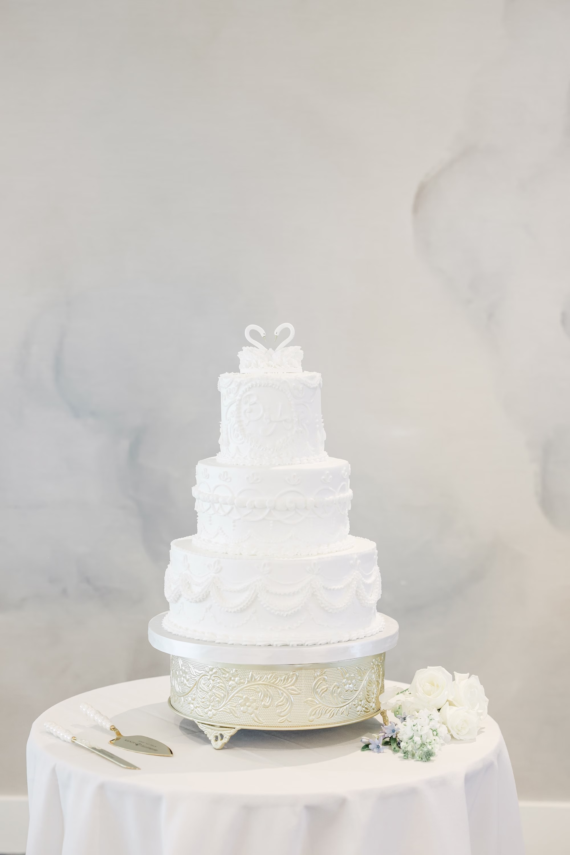 Elegant Monochromatic White Three Tier Wedding Cake on Gold Stand Wedding Reception Decor Inspiration | Swan Cake Topper Decor Ideas