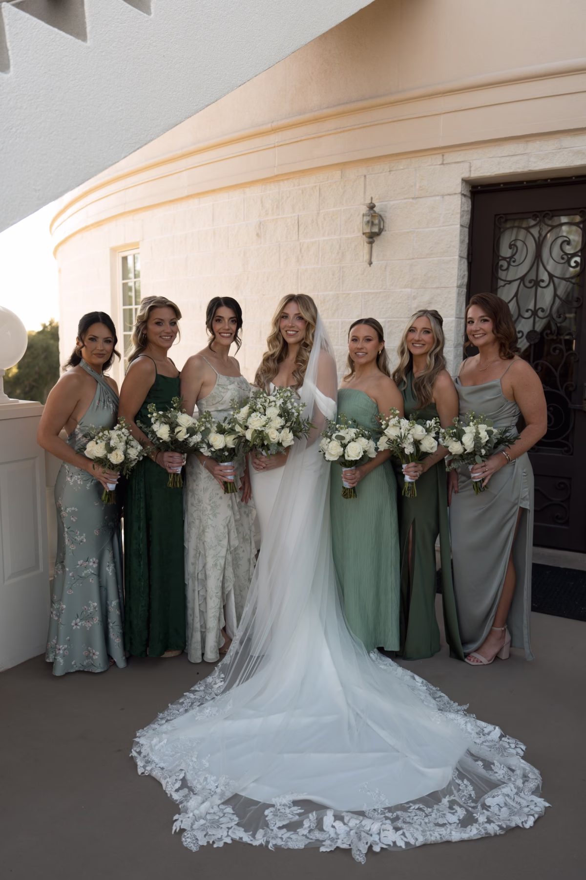 Bride and Bridesmaids Wedding Portrait | Elegant Form Fitting White Wedding Gown with Off the Shoulder Neckline with Train and Floral Detailed Cathedral Length Veil Inspiration | Classic White Roses with Greenery Bridal Bouquet Ideas | Olive Green and Floral Mismatched Bridesmaid Dresses Inspiration | Tampa Bay Photographer Amber Yonker Photography