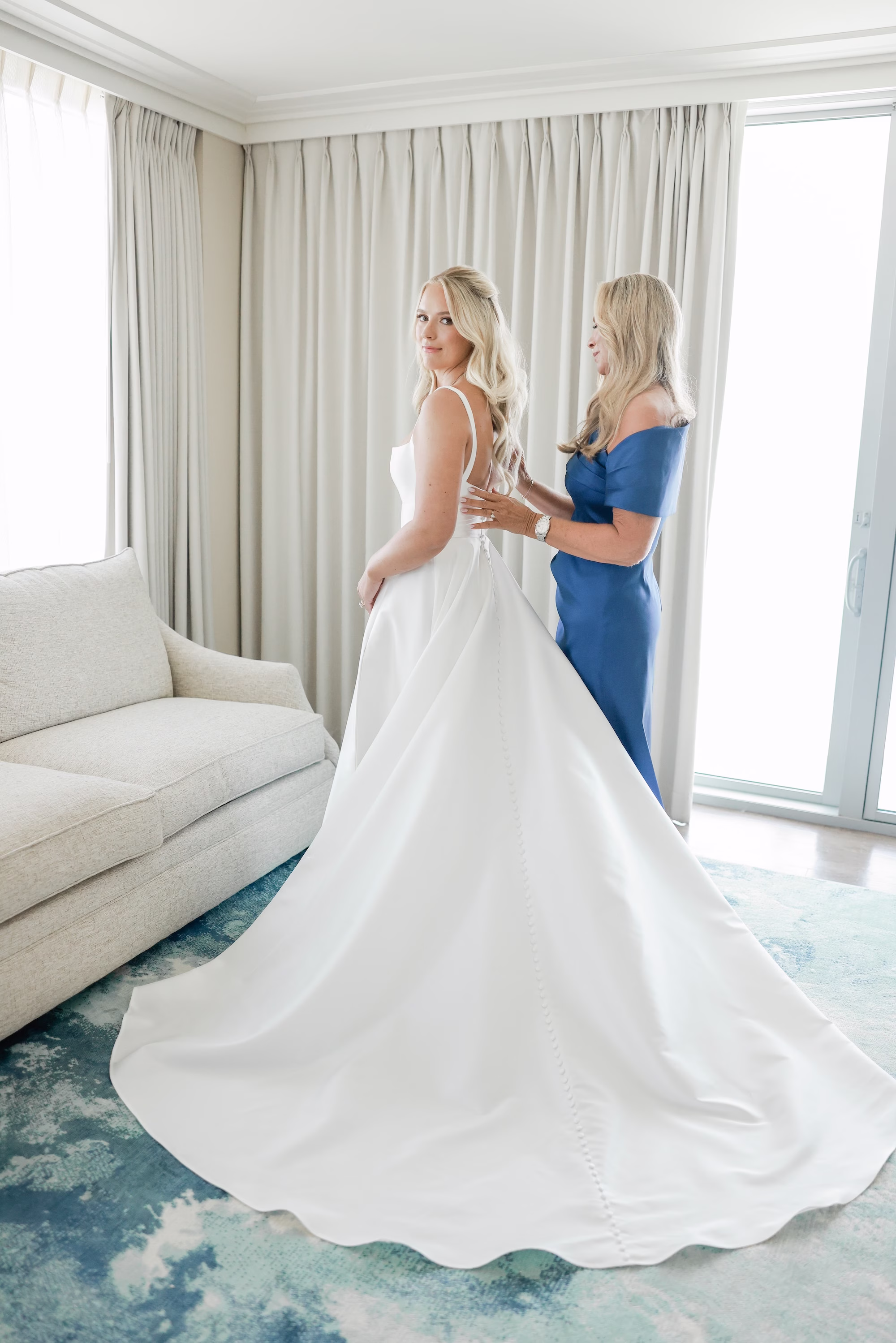 5Elegant Light Blue Coastal Florida Wedding Ideas - Elegant Blue Modern Coastal Wedding | Opal Sands Clearwater Beach Mother Helping Bride into Ivory Satin Ballgown Wedding Dress Getting Ready Portrait in Oceanfront Suite