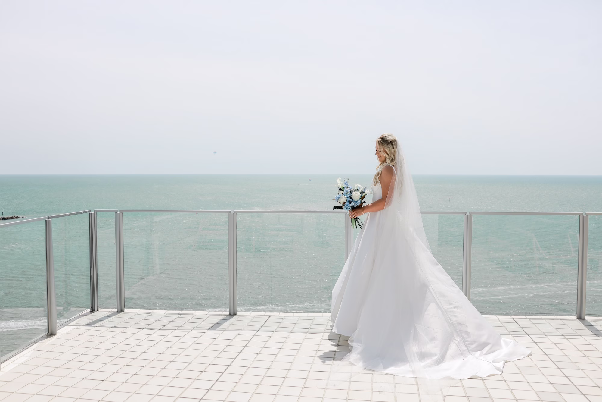 6Elegant Light Blue Coastal Florida Wedding Ideas - Elegant Blue Modern Coastal Wedding | Opal Sands Clearwater Beach Bride in Ivory Satin Ballgown and Cathedral Veil on Gulf-Front Balcony with Blue and White Bouquet Bridal Portrait | Clearwater Beach Venue Opal Sands Resort | Photography Lifelong Photography Studio