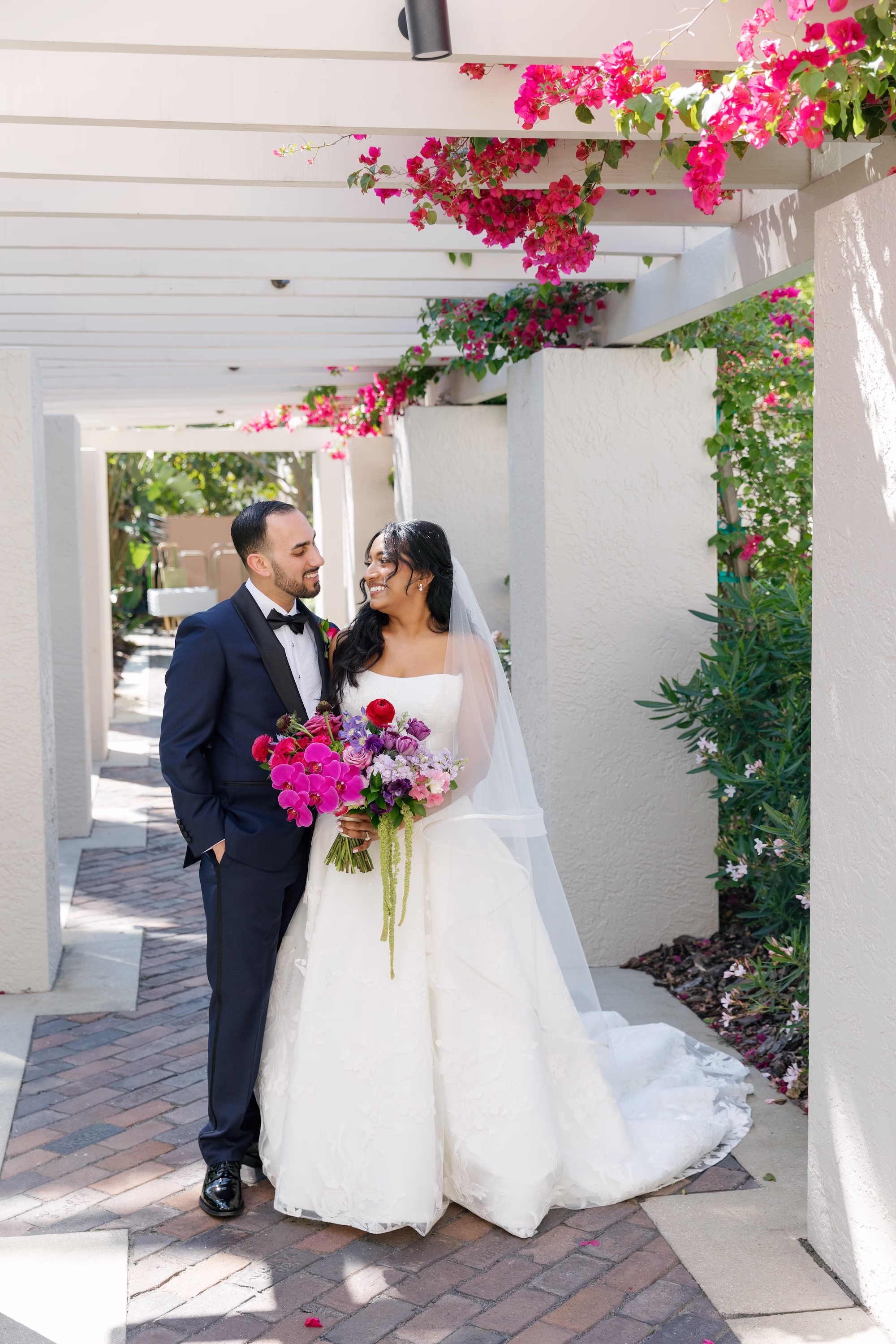 Bride and Groom Wedding Portrait Under Pink Bougainvillea Pergola with Vibrant Pink and Purple Bouquet | St. Pete Florist Bruce Wayne Florals