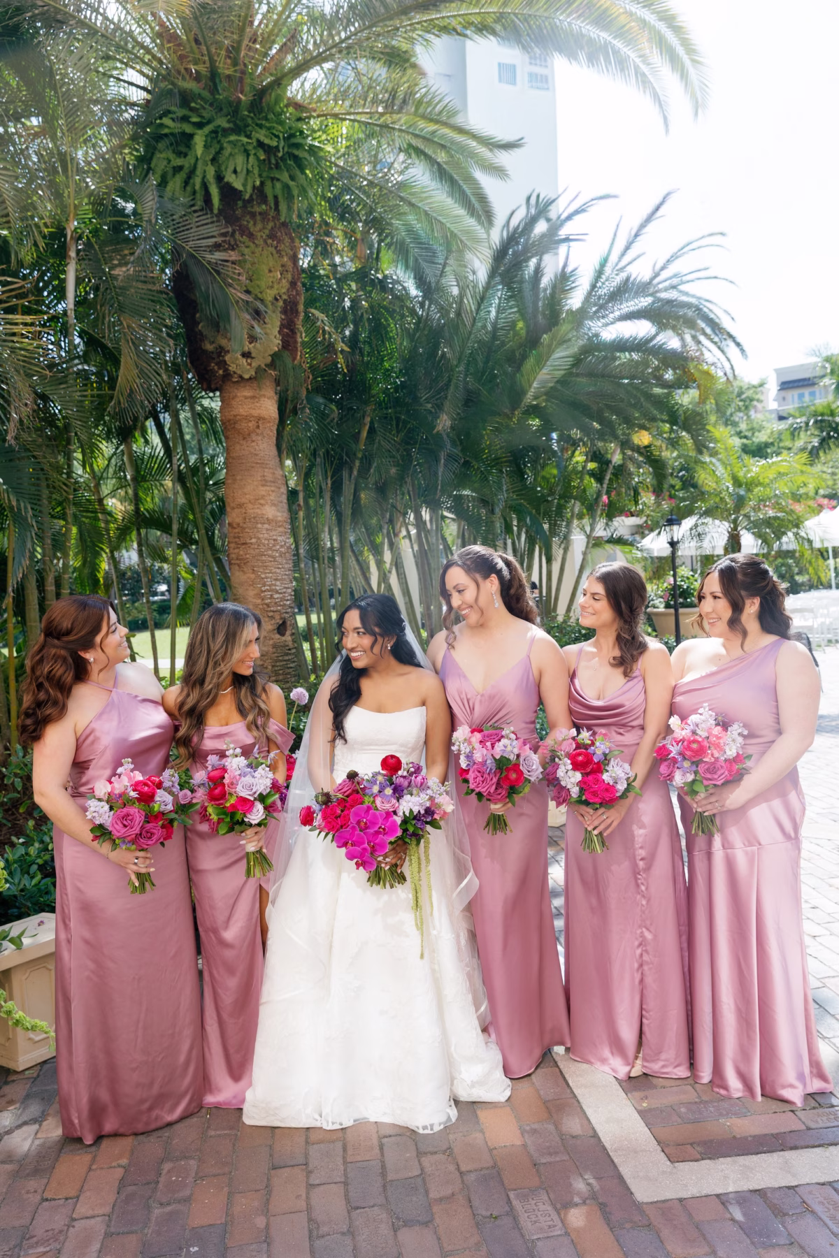 Bride and Bridesmaids Wedding Party Portrait in Dusty Rose Satin Mismatched Bridesmaid Dresses with Pink and Purple Bouquets | St. Pete Florist Bruce Wayne Florals