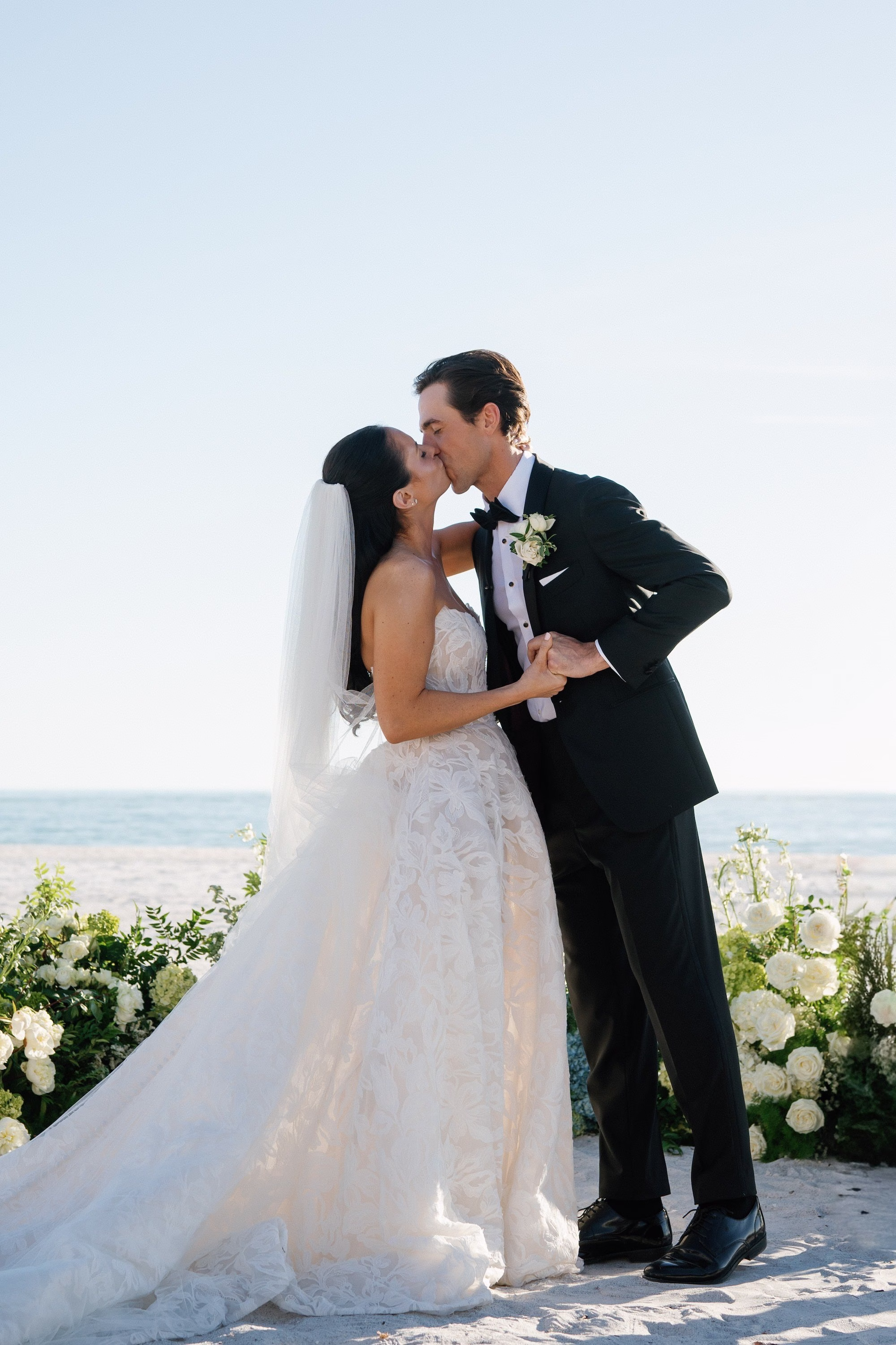 19Coastal Nancy Meyers Inspired Florida Beach Wedding - Coastal Blue, White, and Green Sarasota Wedding | The Resort at Longboat Key Club Bride and Groom First Kiss Beach Wedding Portrait with White Hydrangea Floral Altar and Gulf of Mexico Behind Them