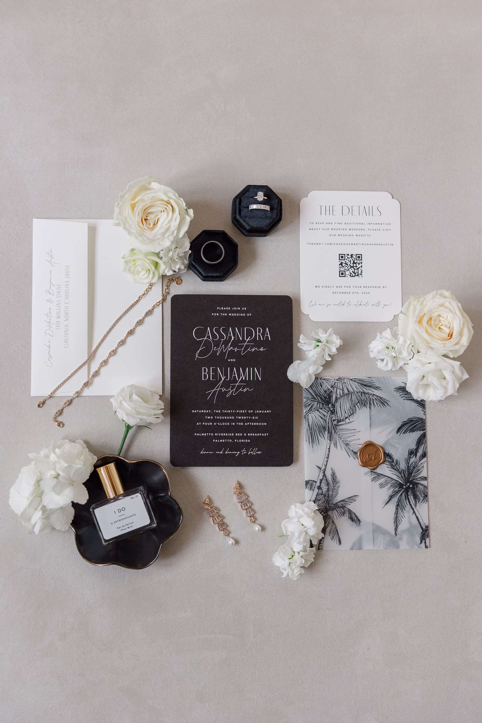 Modern Black and White Wedding Invitation Suite Flat Lay with Palm Print Vellum Wrap, White Roses, Perfume and Pearl Earrings Ideas