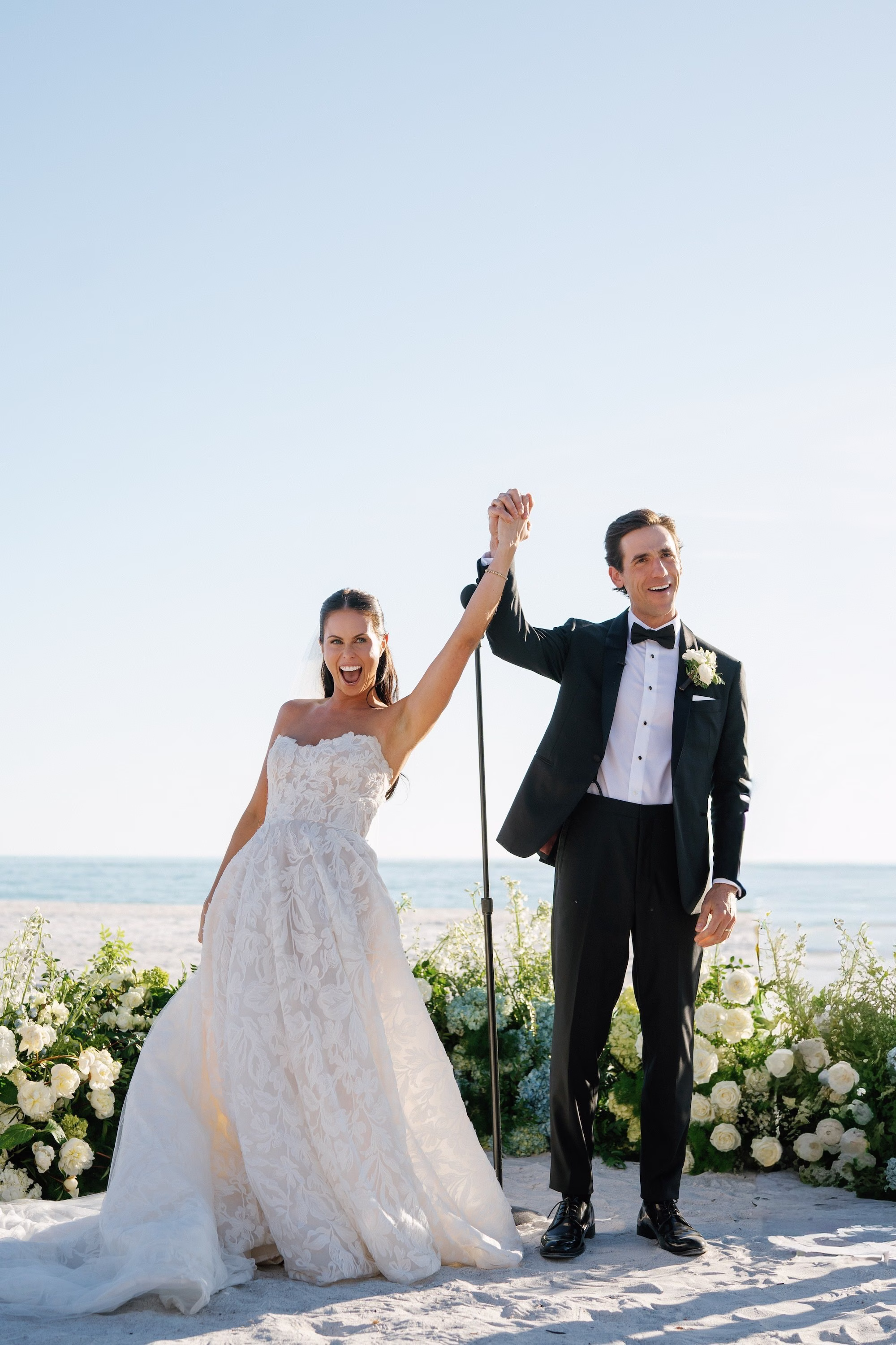20Coastal Nancy Meyers Inspired Florida Beach Wedding - Coastal Blue, White, and Green Sarasota Wedding | The Resort at Longboat Key Club Bride and Groom Celebrating with Arms Raised After Beach Wedding Ceremony Portrait
