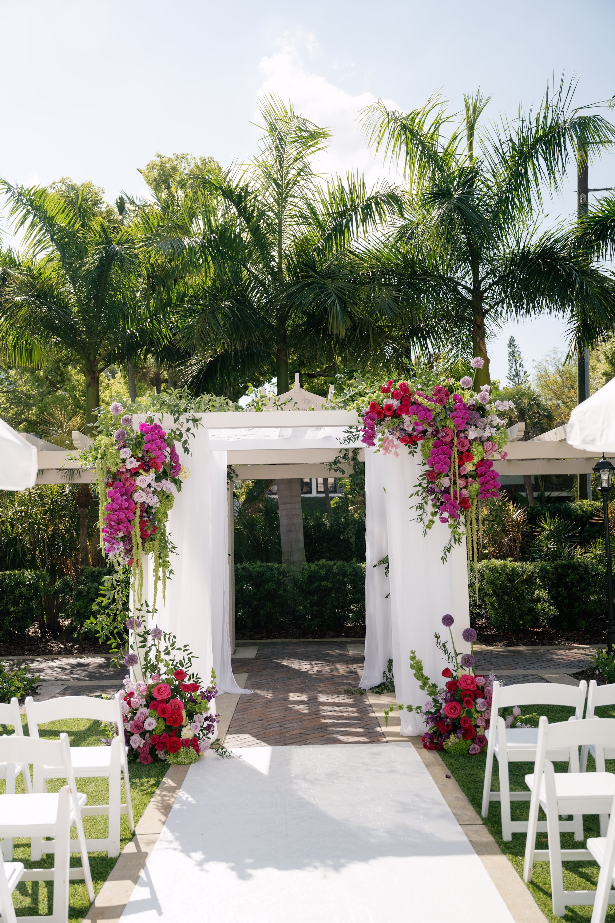 White Draped Chuppah with Cascading Fuchsia Orchid, Pink Bougainvillea and Purple Floral Arrangements Jewish Wedding Ceremony Arch Ideas | Tea Garden Wedding Ceremony at St. Pete Venue The Vinoy | Planner Parties A' La Carte | Florist Bruce Wayne Florals