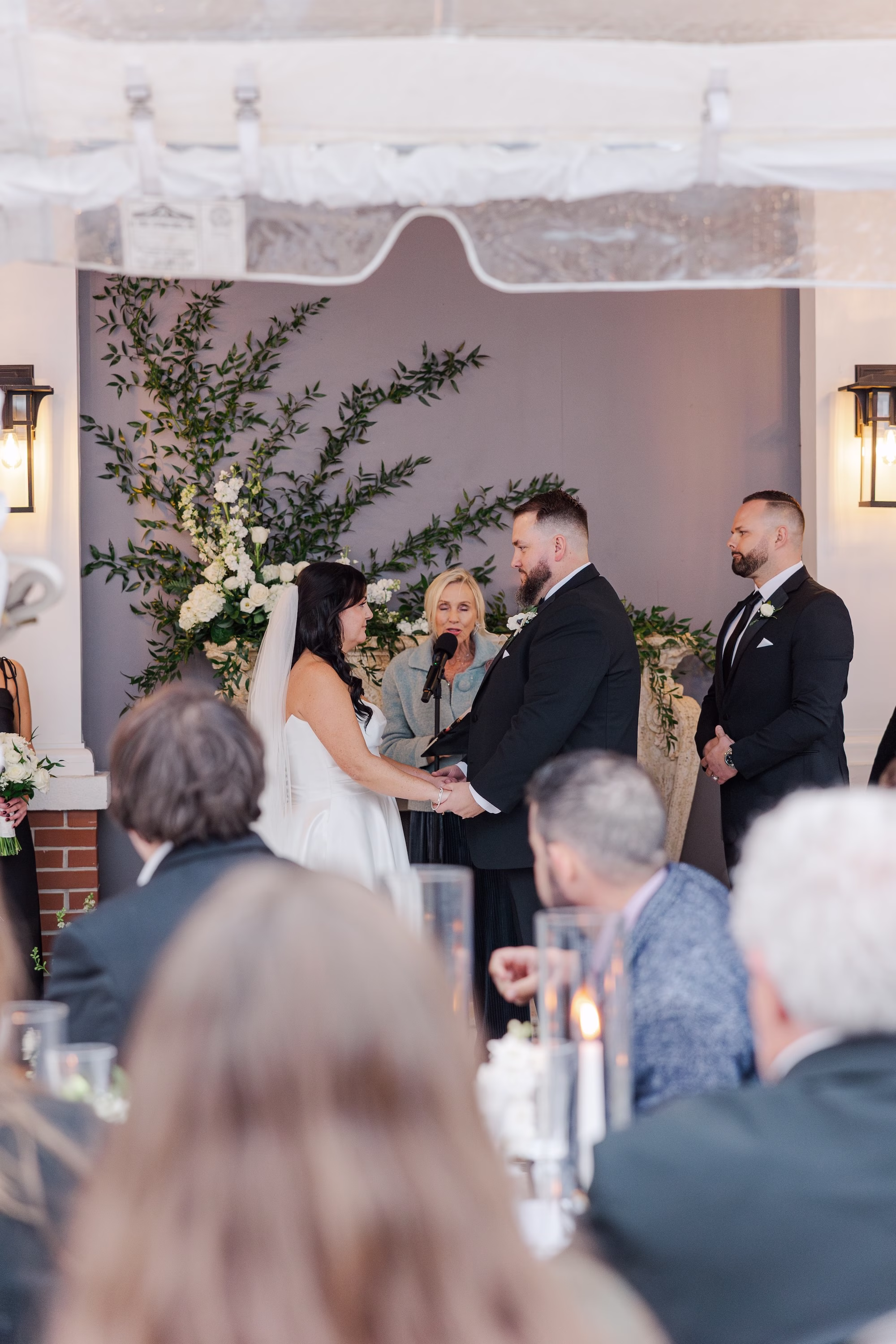 Bride and Groom Wedding Ceremony on Clear Tented Porch with Greenery Fireplace Backdrop | Wedding Ceremony at Palmetto Venue Palmetto Riverside Bed and Breakfast | Officiant Laurie Chandler Celebrant